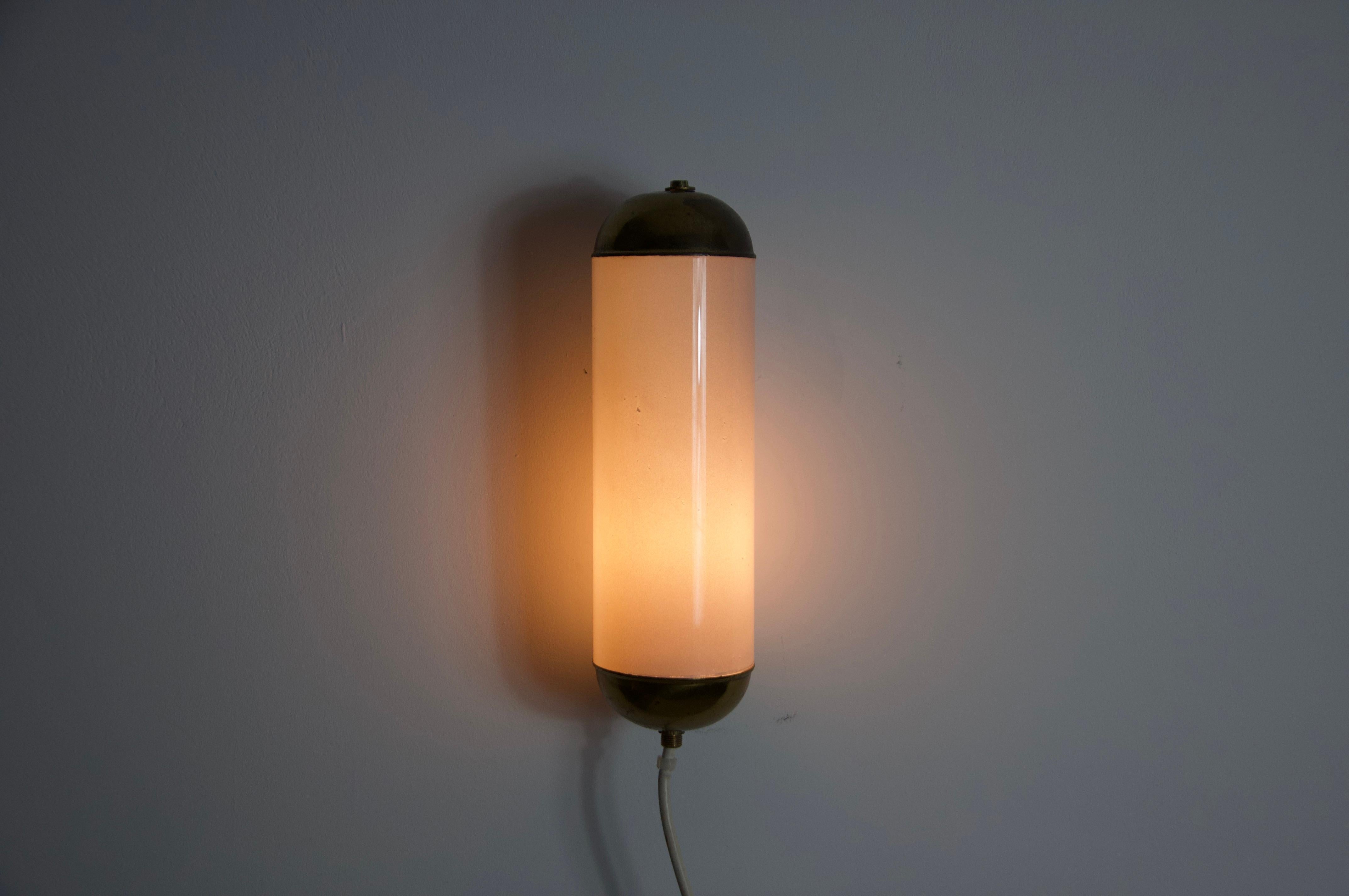 This distinguished Limburg wall lamp, crafted in the 1960s, exemplifies the superior quality and precision of German workmanship. The lamp is elegantly designed with a brass frame that encases a refined opal glass shade, which is securely rotated