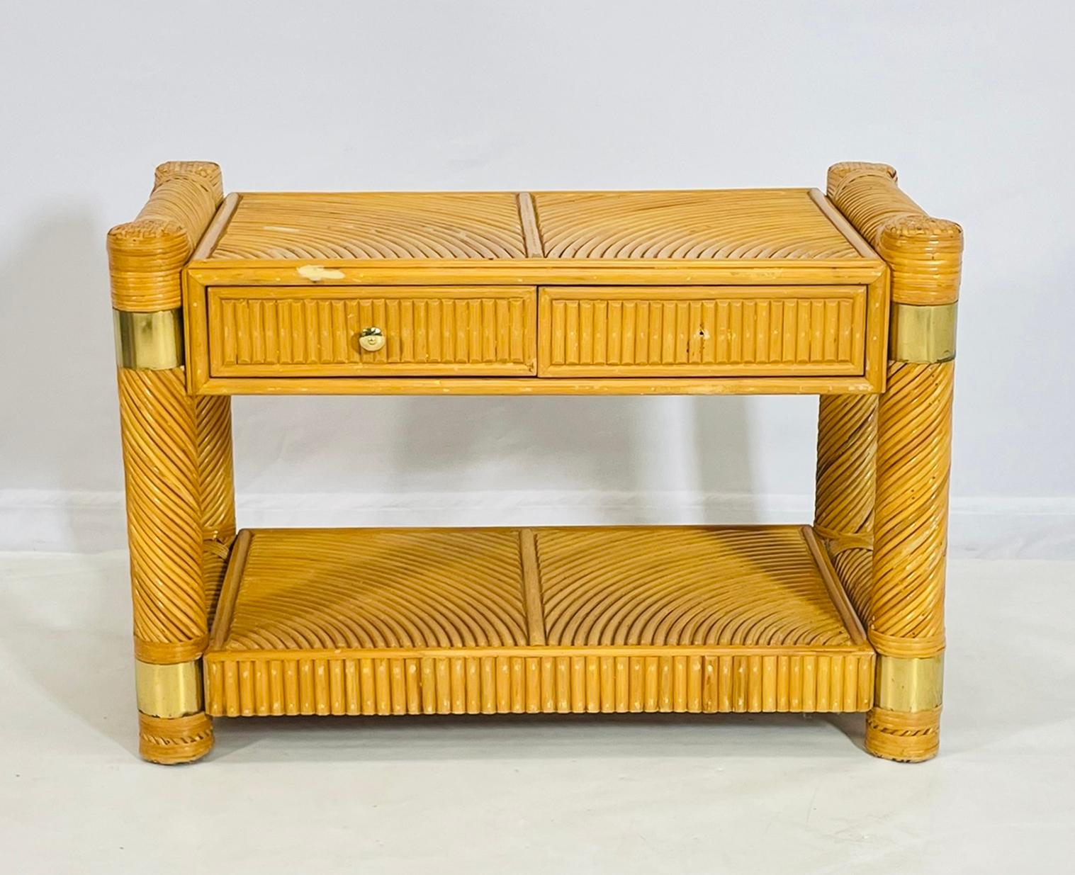 Belle et élégante table console conçue et fabriquée aux États-Unis dans les années 1970.

La pièce est fabriquée en bois massif avec un design en forme de roseau et des accents en laiton.

L'armoire est équipée de 2 tiroirs et possède deux niveaux,