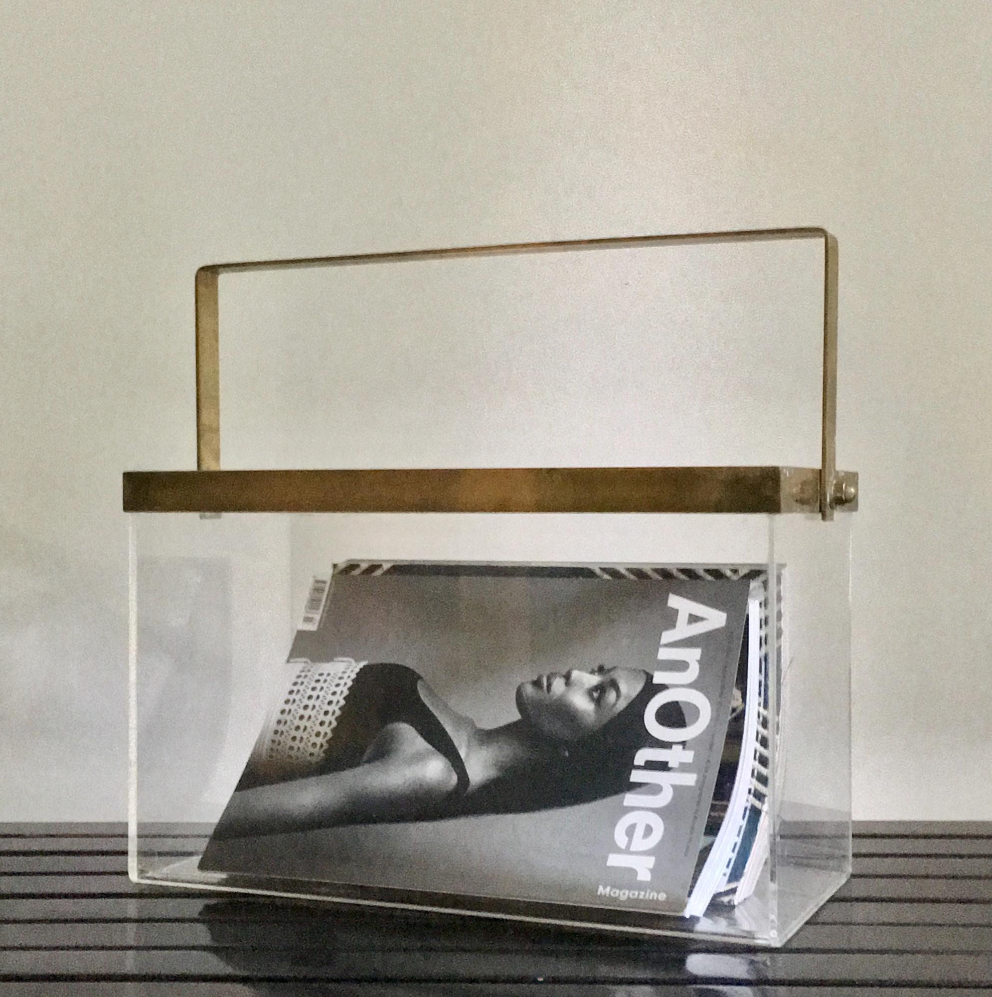 Nice, simple magazine holder of bent-plexiglass with brass handle and trim. European 1970s.

Very nice piece, stylish and practical, which presents well and could work in many spaces. Good original condition. Lots of patina to the brass and light