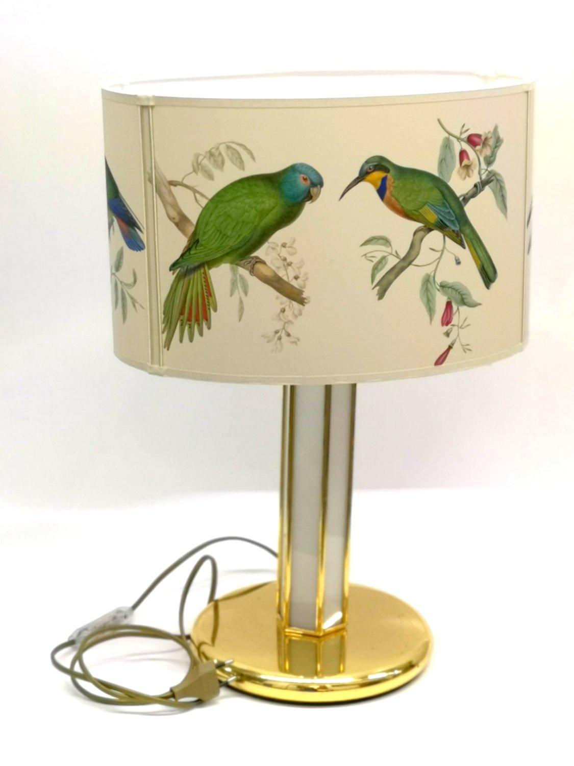 This table lamp of elegant simplicity comes with a uniquely manufactured parrot styled lamp shade. The metallic and matte white surfaces perfectly complement the calm colors and design of the shade.