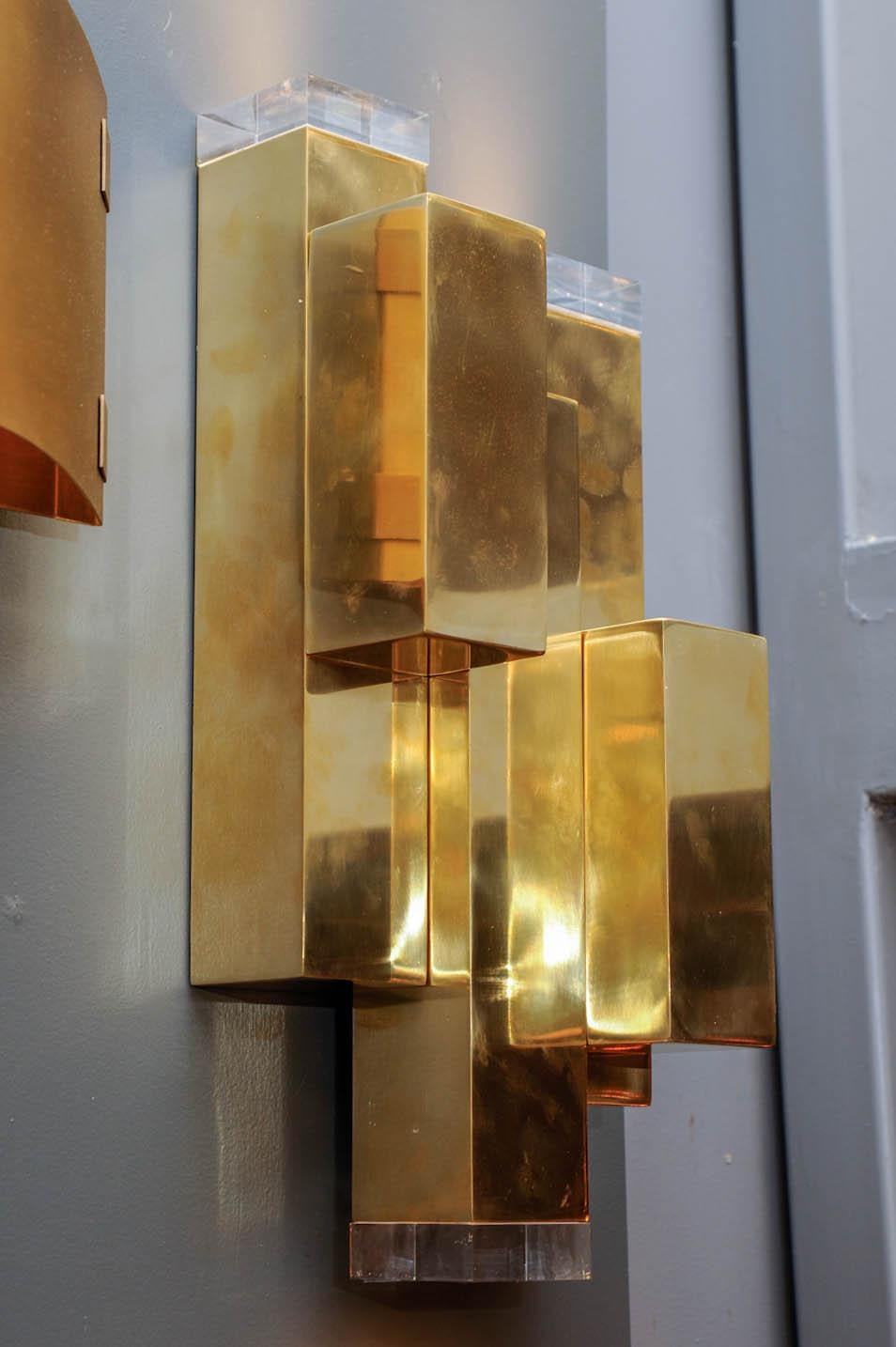 Wall sconces made of five square brass unit of different sizes put together with plexiglass inserts helping to diffuse the light.