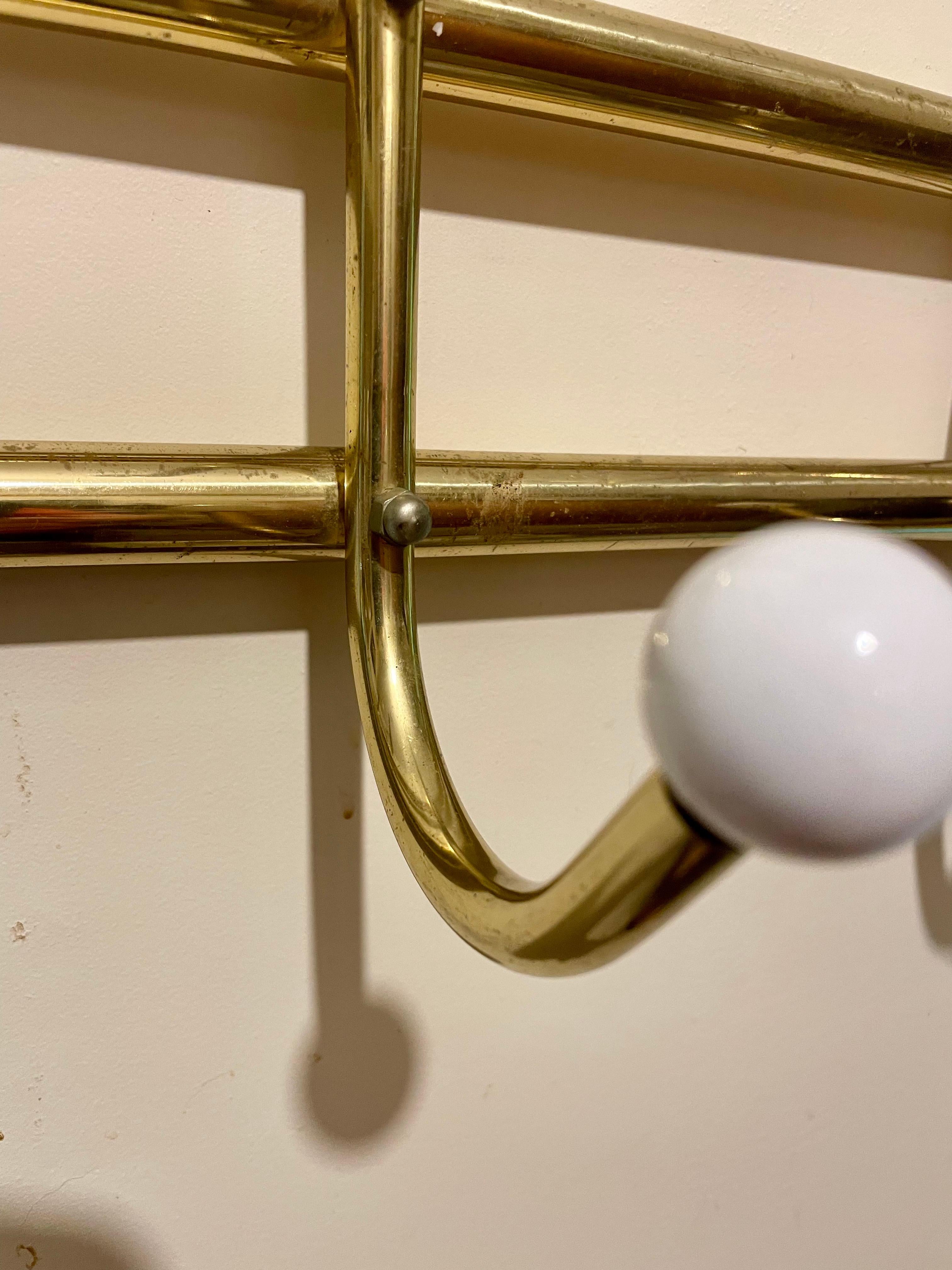 Appendiabiti da parete in ottone e porcellana in stile Hollywood Regency. Cinque grandi ganci doppi e resistenti per contenere cappelli e cappotti. circa 1970-1980. Usura coerente con l'età, compresa una leggera patina dovuta all'età e all'uso.
