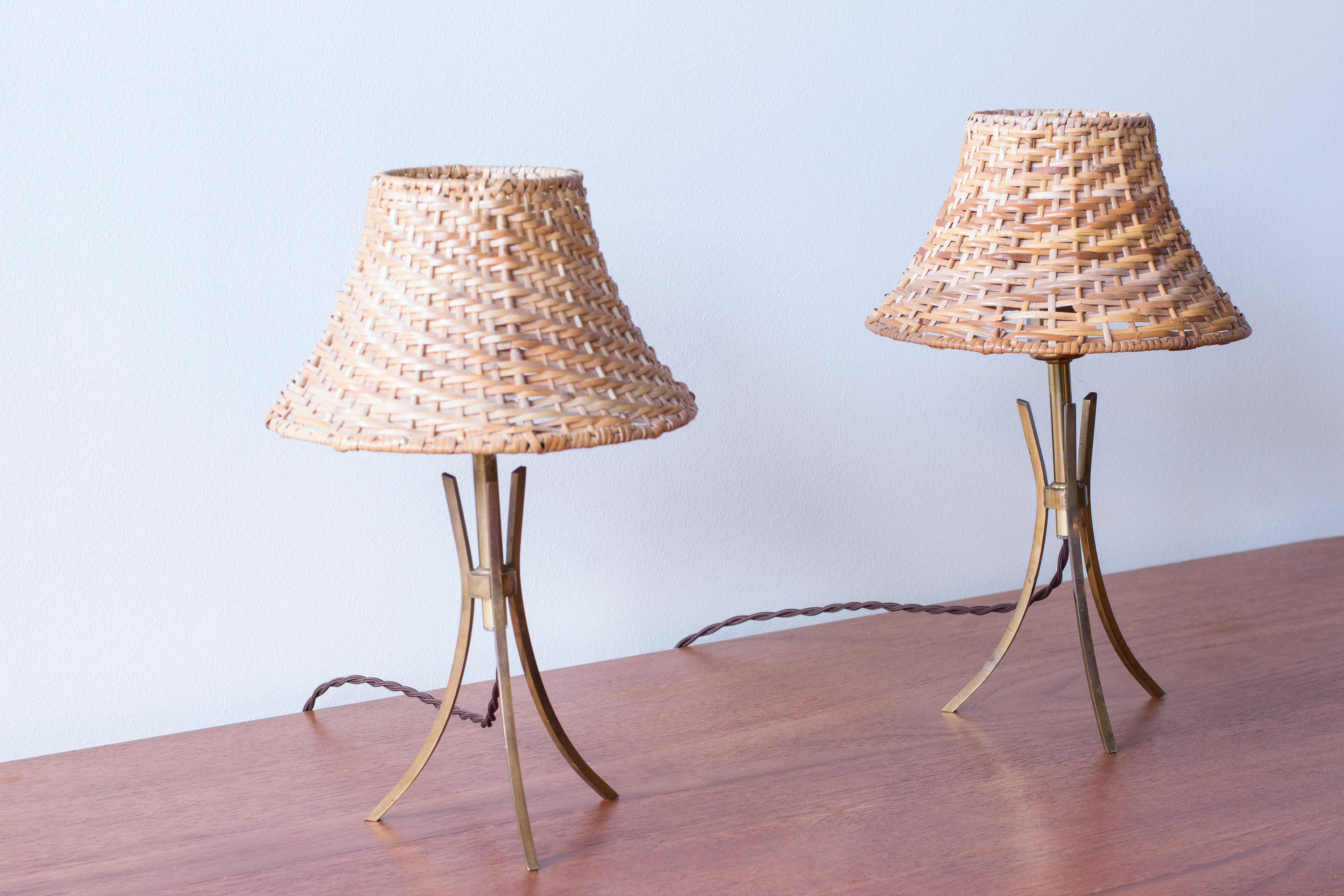 Pareja de lámparas de mesa diseñadas y fabricadas en Suecia durante los años 40-50. Fabricada en latón macizo sobre una cuidada base de trípode, con pantallas de ratán que dan una luz cálida y hermosa cuando están encendidas. Interruptores de luz