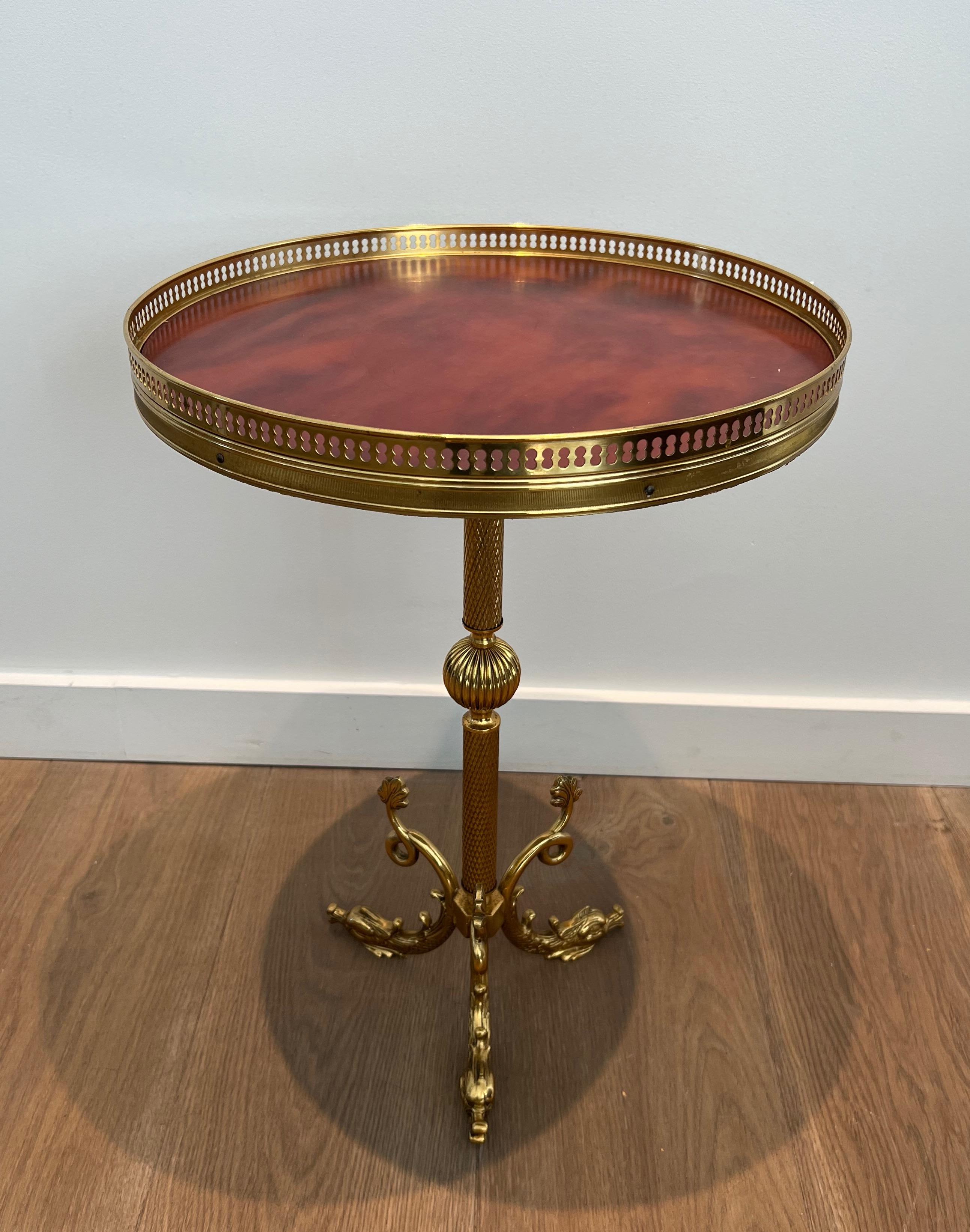 This nice neoclassical style round gueridon i!s made of brass with a red celluloid top. This is a French work after Maison Jansen. Circa 1940