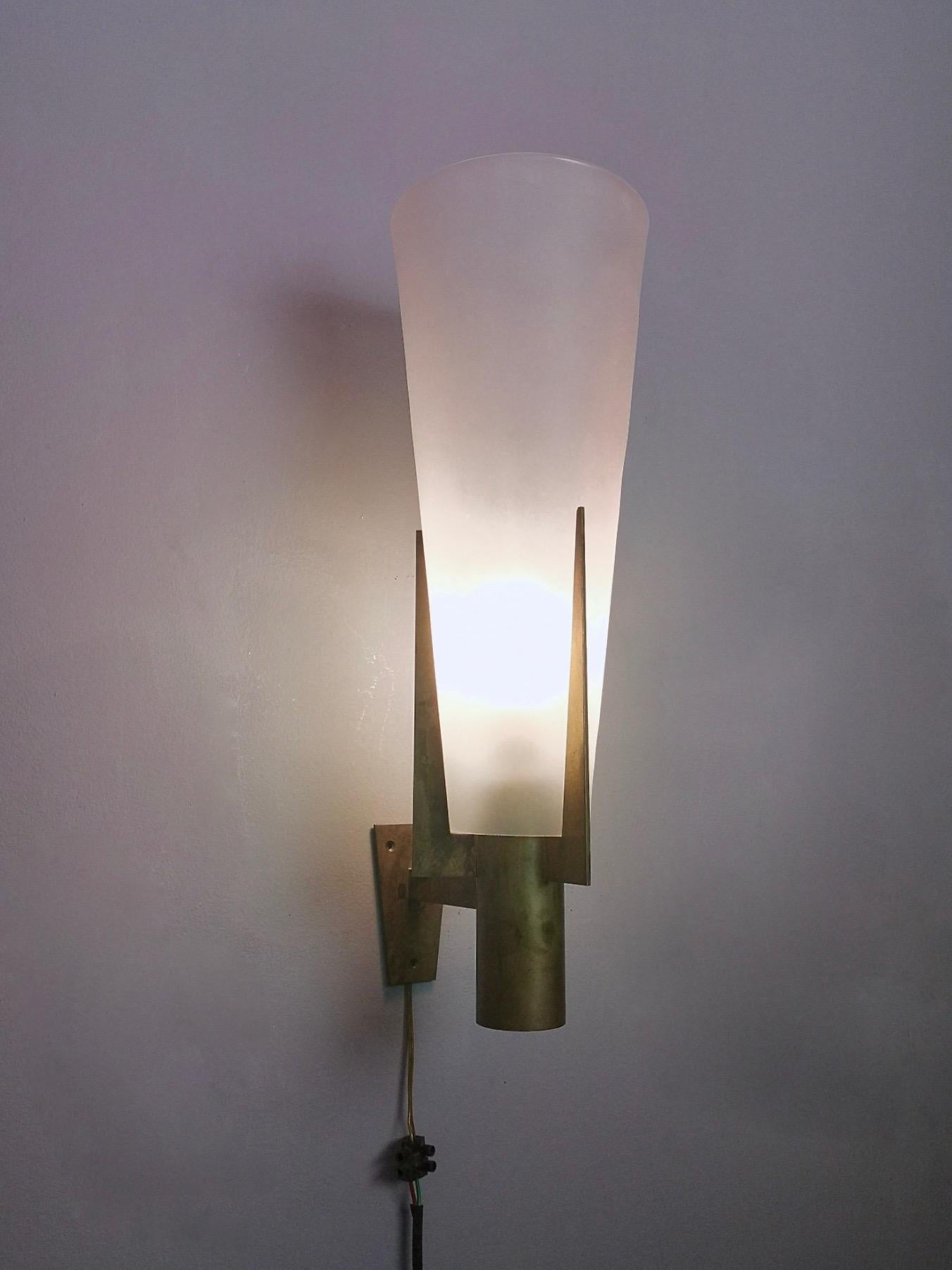 1950s.
This is an elegant and stunning large scale wall sconce by Stilnovo, model 2021.
It features a three pronged brass frame and a conical satin glass lampshade.
It is a vintage item, therefore it might show slight traces of use, but it can be