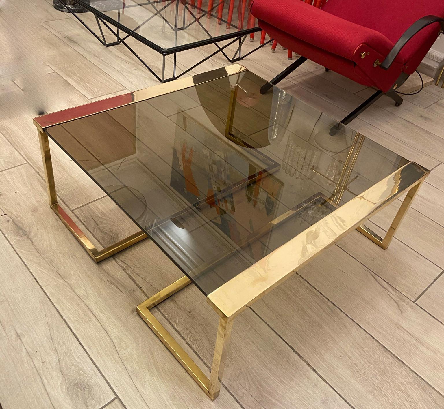 Side table or coffee table in Hollywood regency style from the 70s, brass structure and architecturally shaped legs with smoked glass shelf.
 The coffee table, made in the style of Romeo Rega, is a piece of exceptional manufacturing quality.