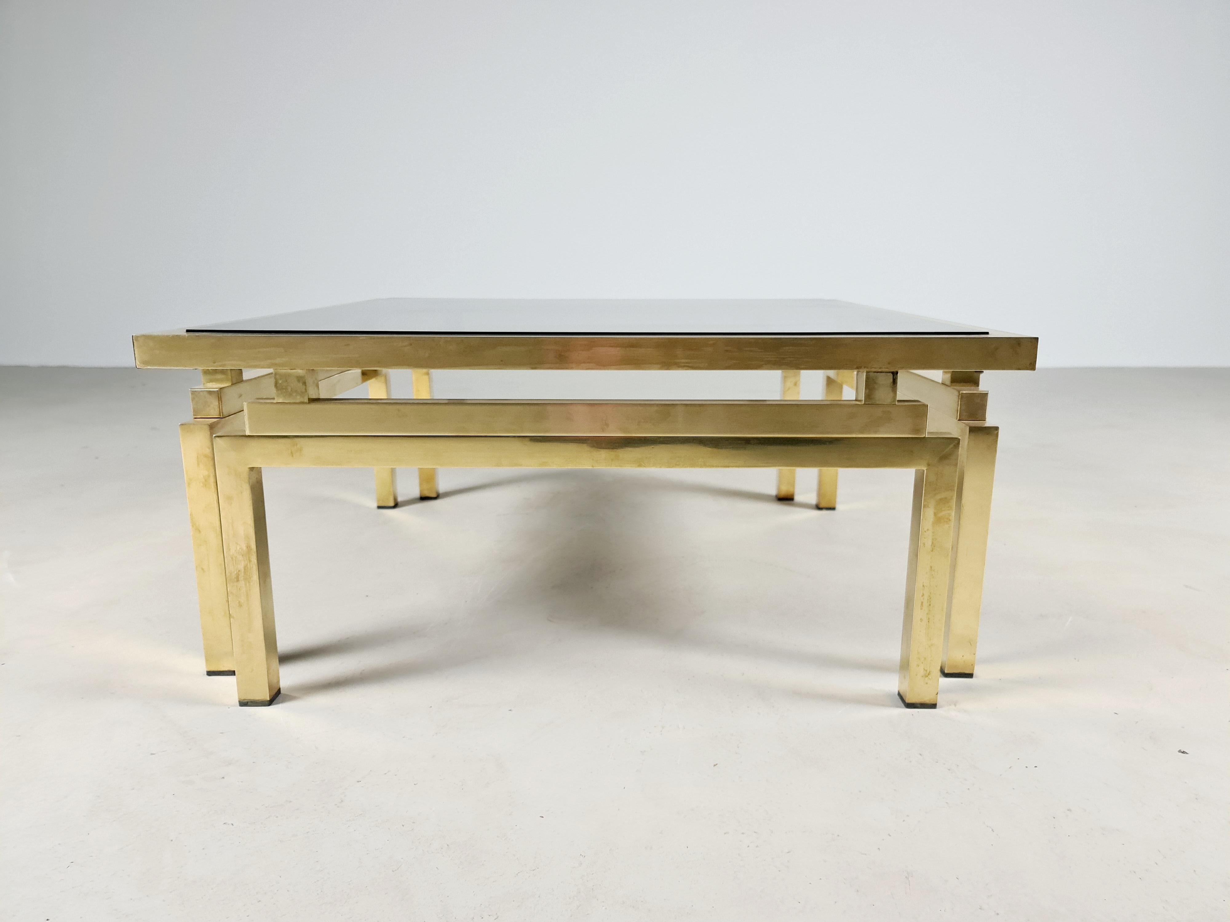 Romeo Rega coffee table in Hollywood regency style from the 70s, brass structure and architecturally shaped legs with smoked glass shelf.
The coffee table is a piece of exceptional manufacturing quality.