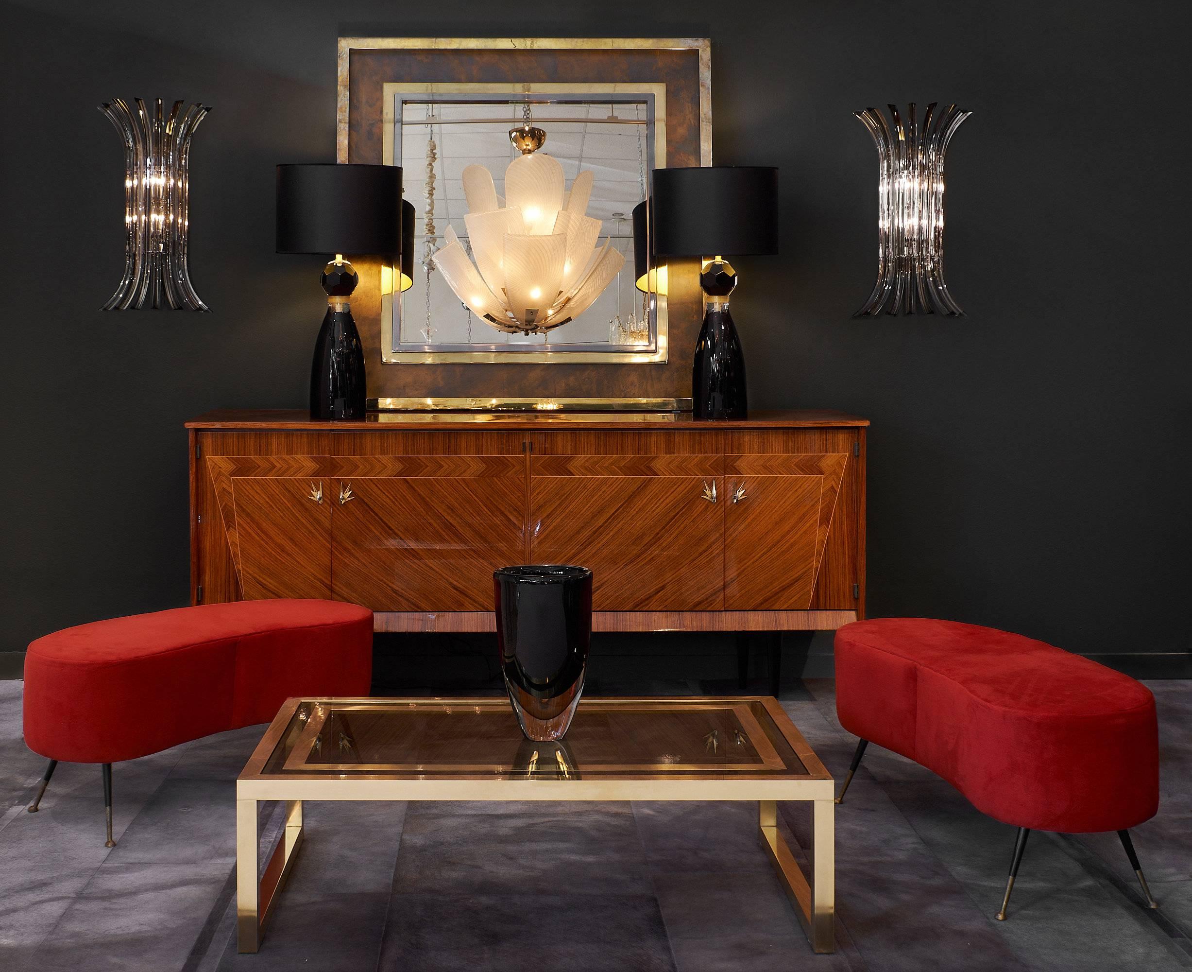 A French Mid-Century Modernist coffee table in brass; with its original smoked glass top featuring a gilt brass trim appliqué. We love the open rectangular sections on each end of the frame’s base; and the strength and boldness of the design.