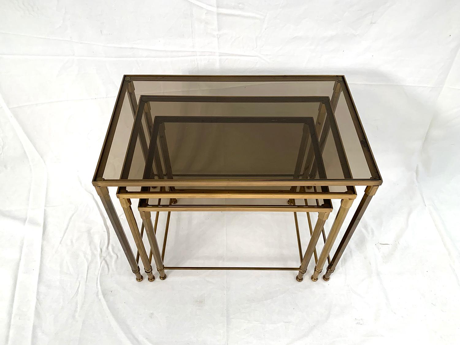 Superb set of brass nesting table topped by smoked glass.

Superbe ensemble de tables gigognes en laiton surmontées par trois de plateaux en verre fumé.