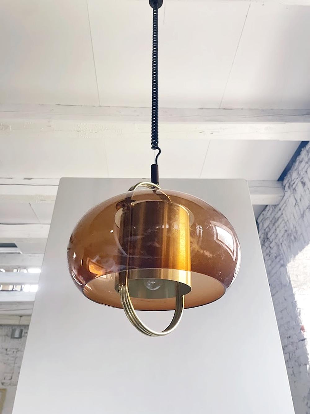Questa lampada a sospensione è stata prodotta da Temde Leuchten, un'azienda di illuminazione tedesca, negli anni '70 nell'ambito del movimento di design Mid-Century Modern. La combinazione di cupola in vetro fumé e anelli in ottone esemplifica