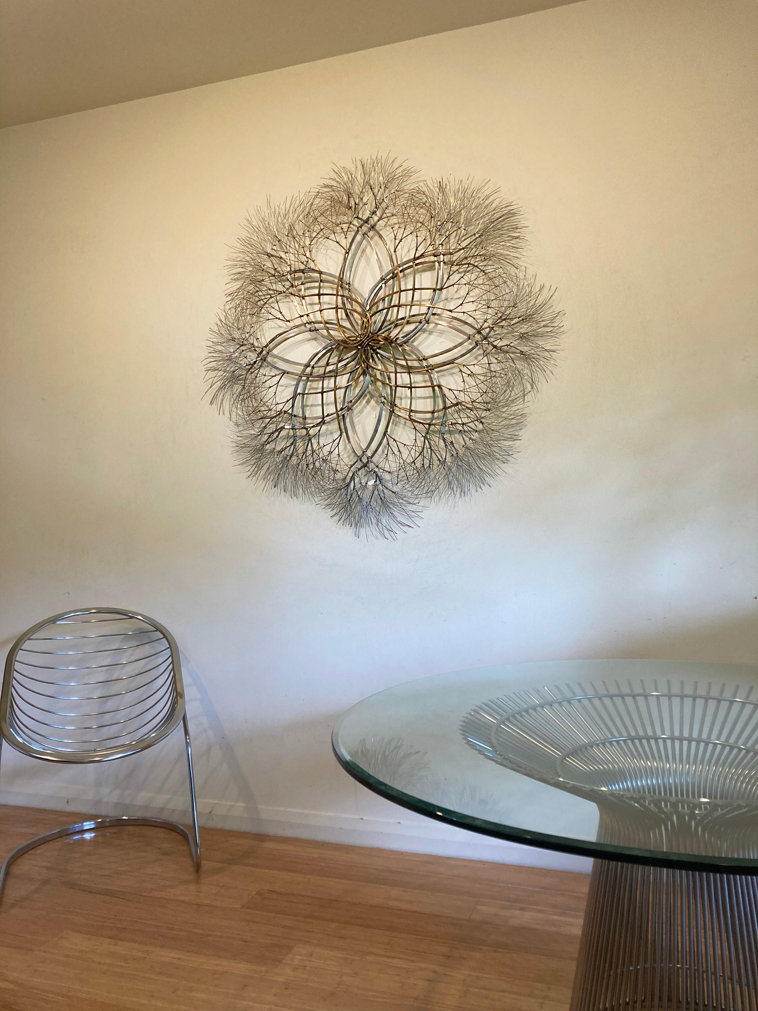 Aged brass, stainless steel. 

Kue King created this wall mounted sculpture using brass and stainless steel wire. The brass is aged to give the sculpture a warmth and depth in color and display. The polished stainless steel gives the sculpture a