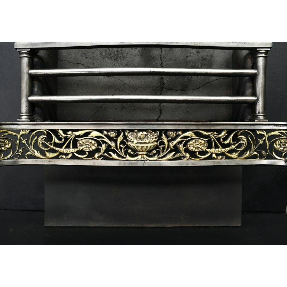 A good quality brass and steel firegrate in the Georgian style. The scrolled legs with rosette detailing surmounted by classical brass urn. The fret with scrollwork, foliage and floral motifs throughout, with polished steel front bars and brass