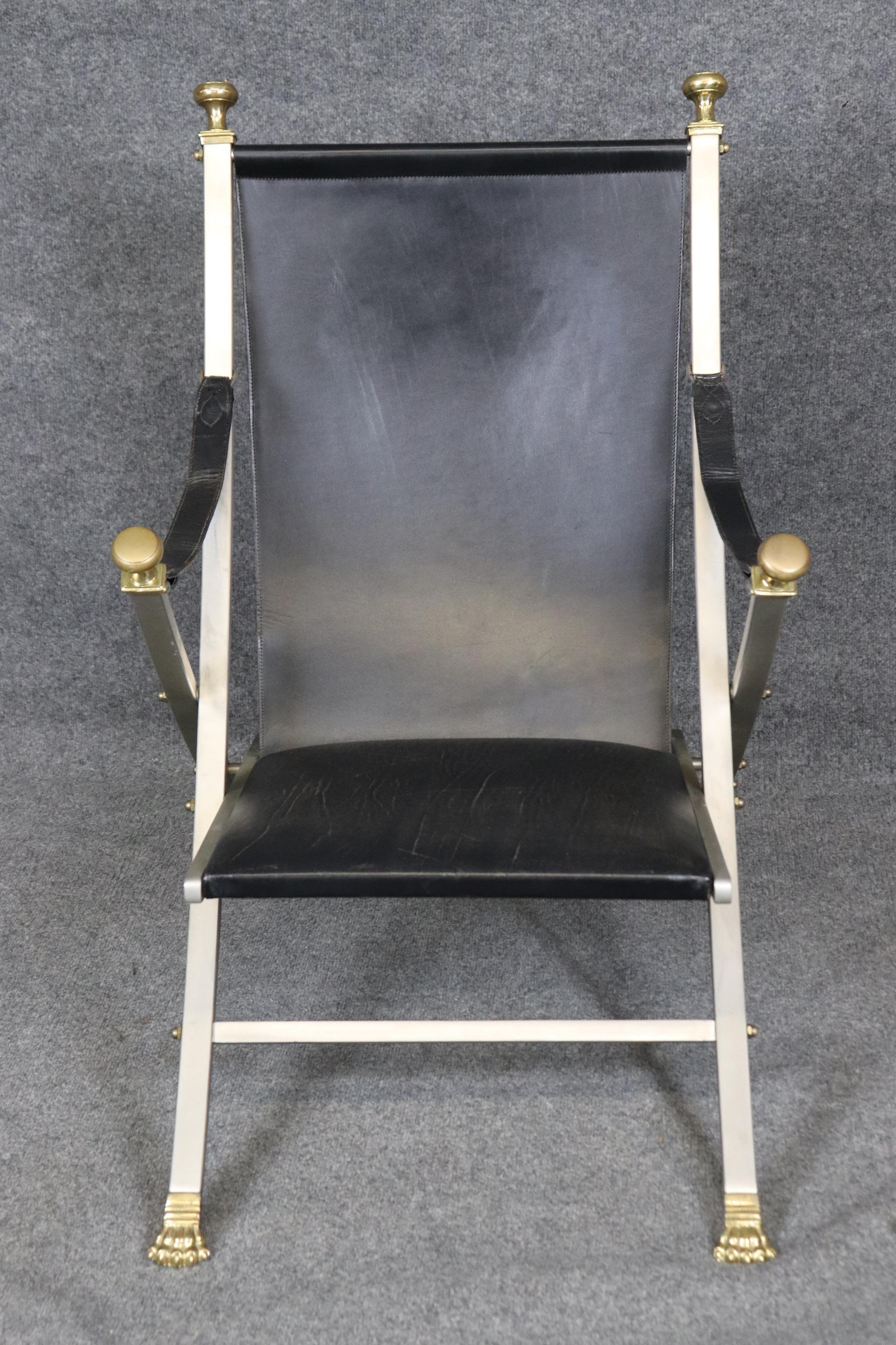 This is a beautiful Maison Jansen brass and steel campaign chair in leather. The chair is in good vintage condition with minor signs of age and wear. The chair features gorgeous cast bras or bronze and fine patina to the leather and age cracking.