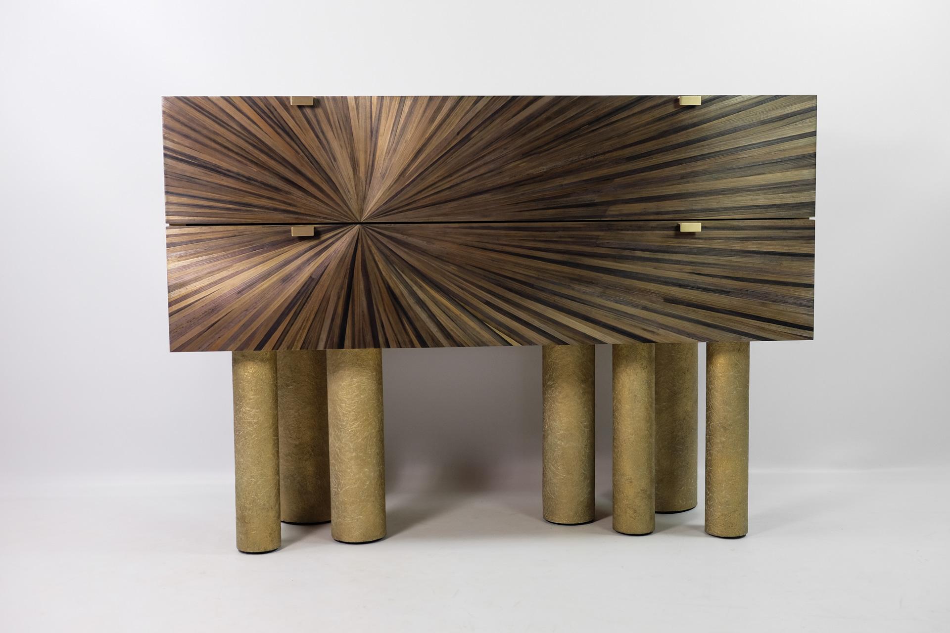 This commode is made of brushed brass on a wood structure.
It has two drawers covered with straw marquetry. 
Each drawer is edged with brass and has brass handles.
 
The interior is veneered with a light oak wood.

It has seven cylinder legs