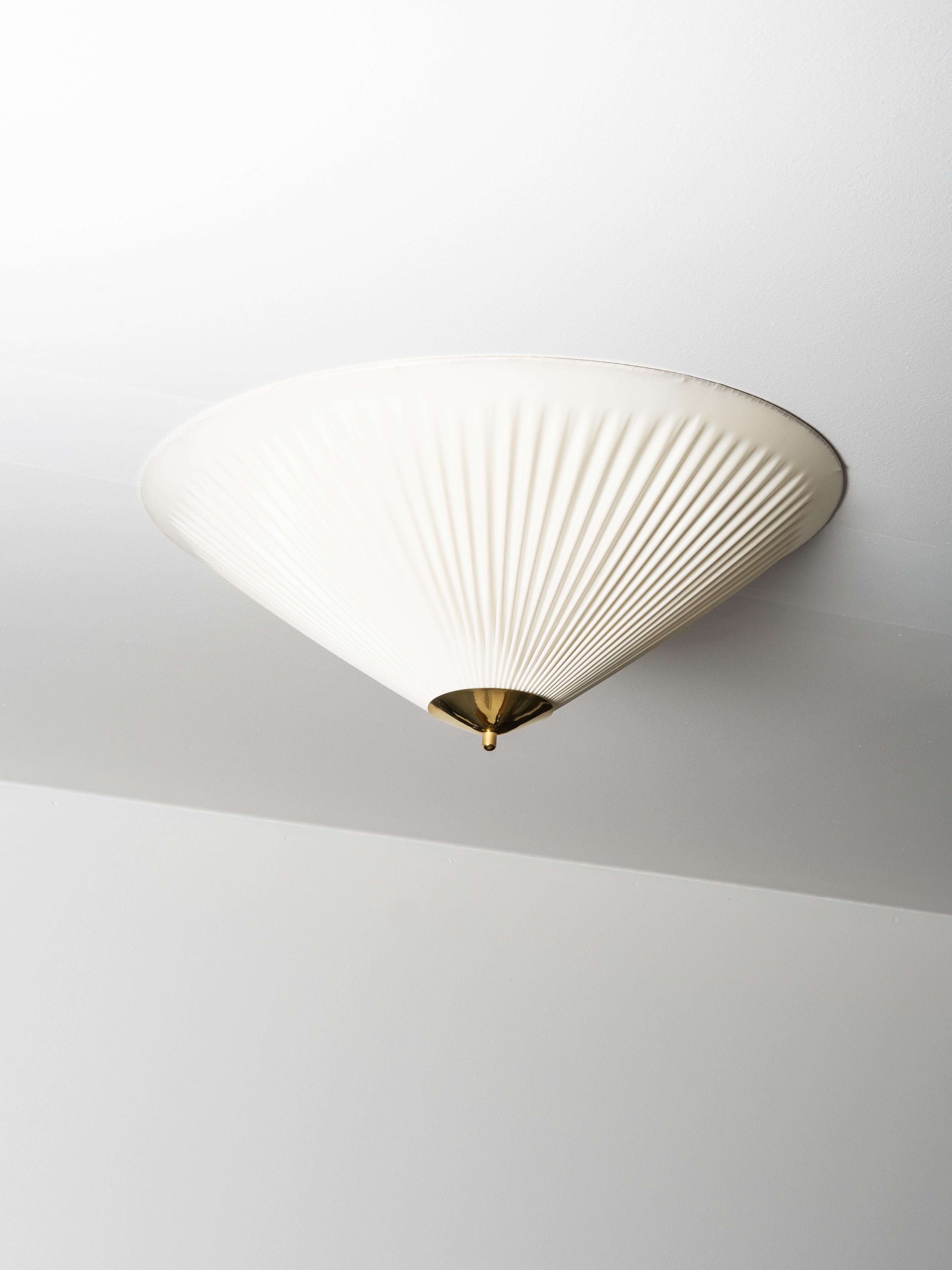 Très belle pièce de Valinte, Finlande, datant des années 1950, dotée d'un abat-jour plissé sculptural en textile synthétique et d'un épi de faîtage en laiton. La forme large et peu profonde crée une lumière douce et uniforme sur le plafond et les