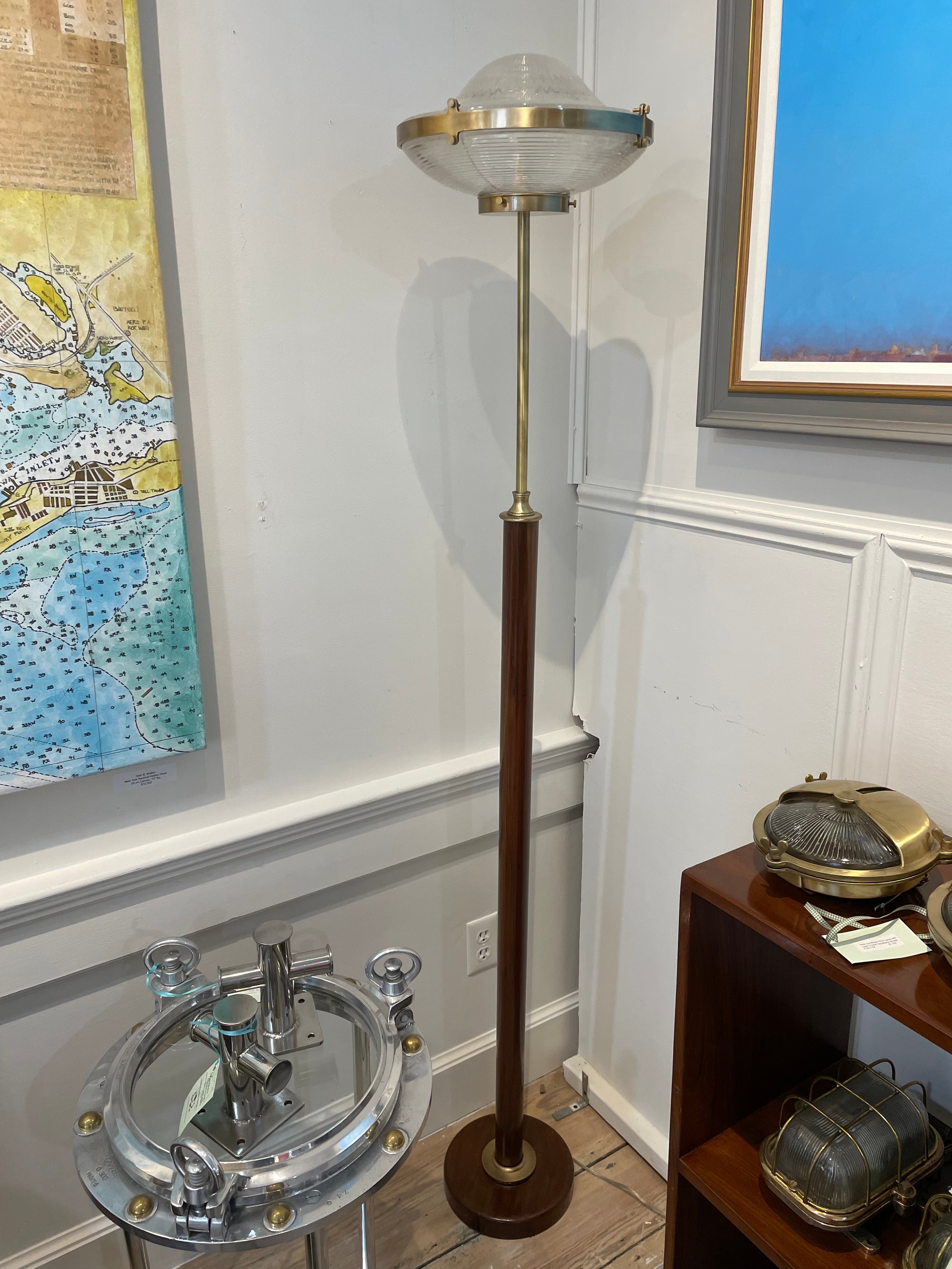 A brass and teak torchière type floor lamp with a lead crystal Holophane shade. The teak base has a 2