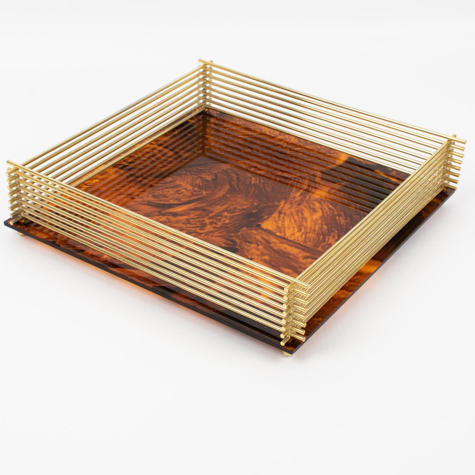 This is a lovely barware serving tray crafted in Italy in the 1970s. The platter or decorative bowl boasts a square shape with a gilded brass raised gallery and a Lucite base with a tortoiseshell (tortoise) textured pattern. This tray is versatile