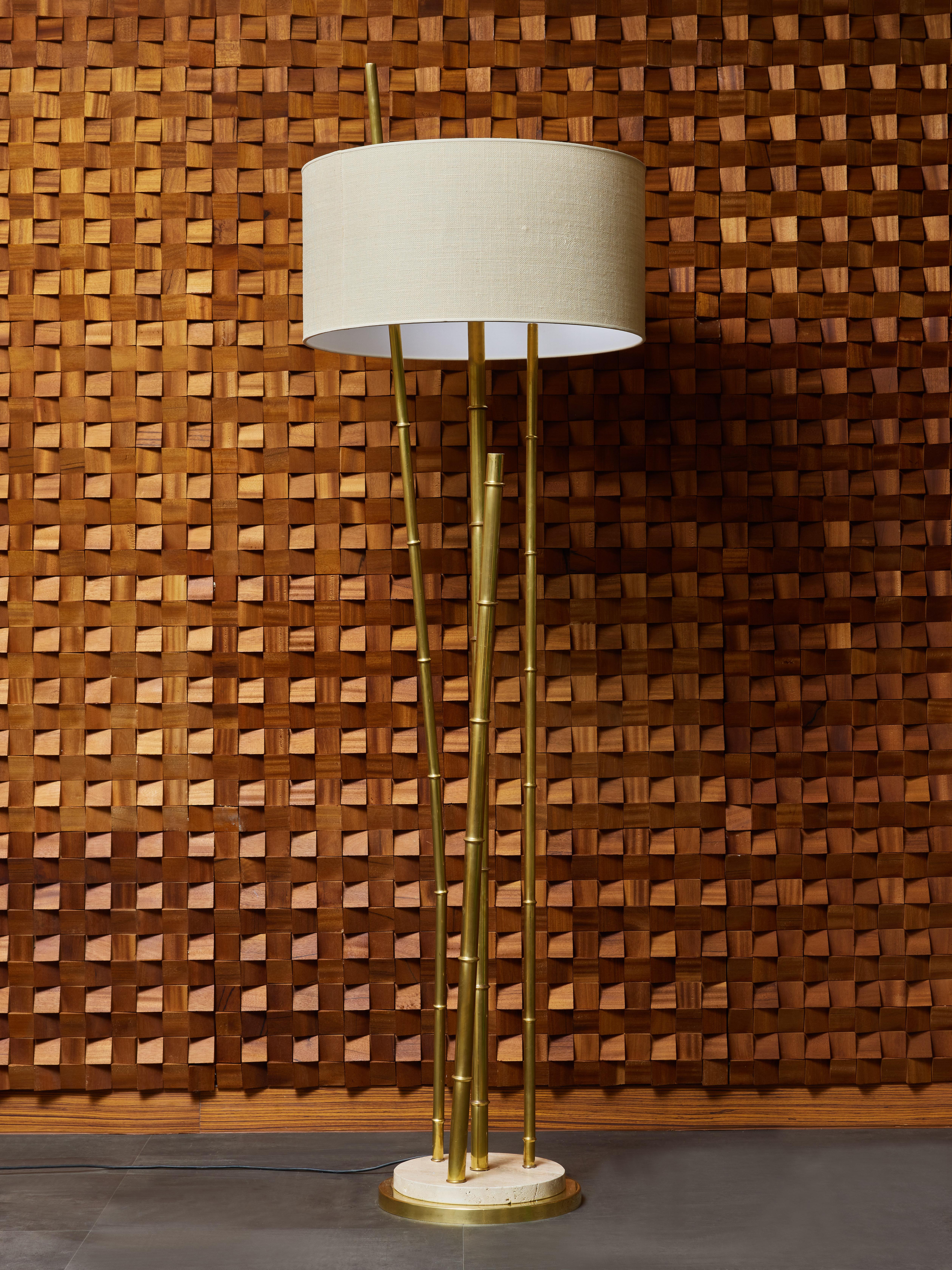 Tall floor lamp made of a circular double base in brass and travertine, bamboo shaped arm of light and decors, topped with a fabric shade.