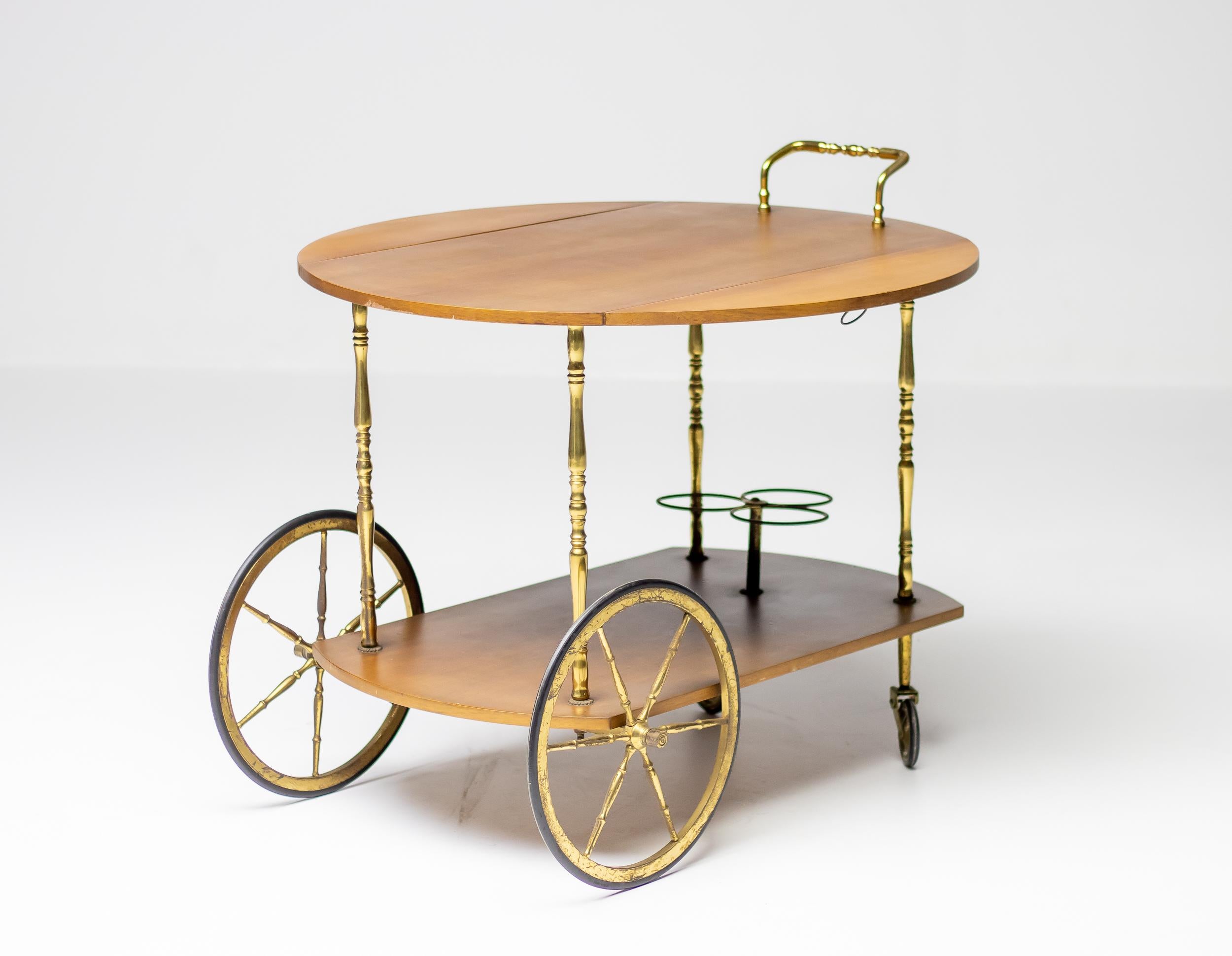 Chariot de bar élégant et pratique attribué à Cesar Lacca, fabriqué en Italie, vers 1965. Plateau rond en noyer, poignées et roulettes en laiton. Le laiton présente une belle patine d'ancienneté, le plateau et les étagères en noyer sont en très bon