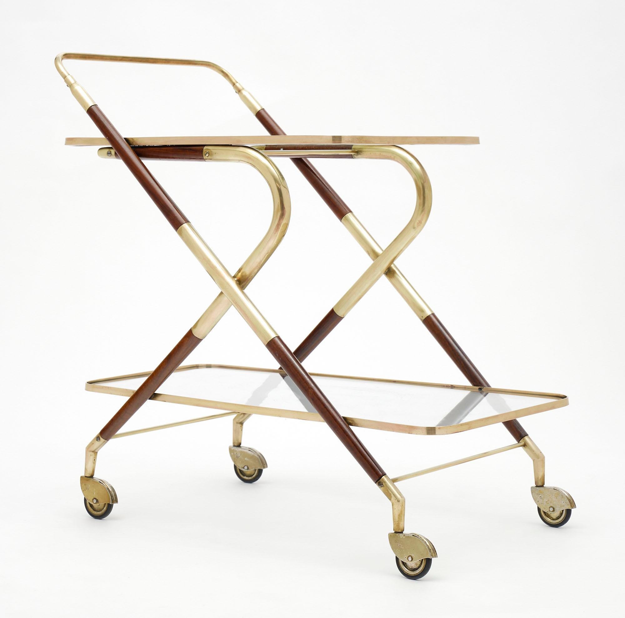Bar cart from Itlay made of mahogany and brass by designer Cesare Lacca. There are two glass shelves as well; and it is supported by original casters.