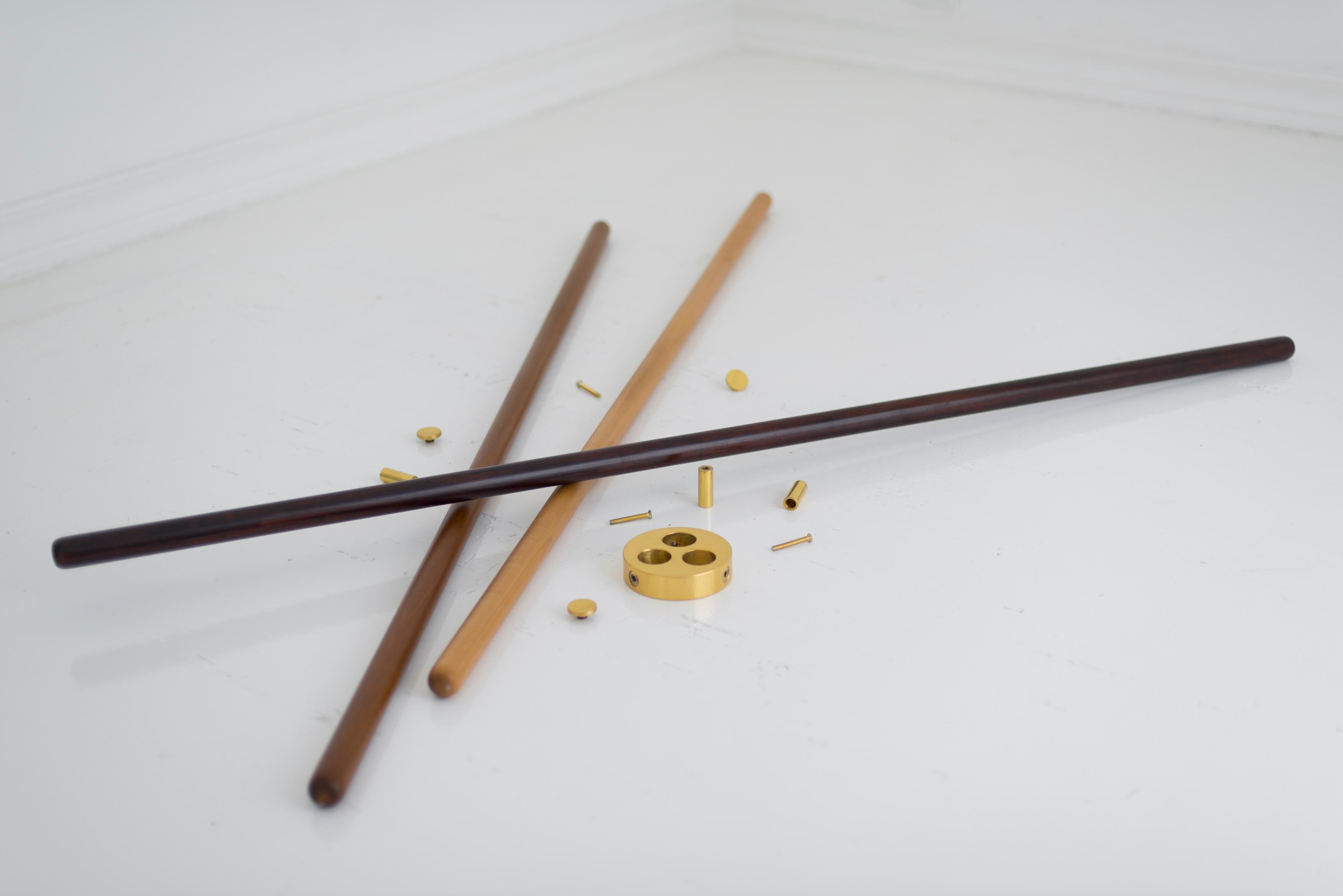 Brass and wood sculpted stool - Leandro Garcia 
Turned wooden rods (light, medium and dark colors) with polished brass disk and pin hangers
Dimensions: 165 x 50 x 50 cm

The Varetas (“Sticks”) coat Stand consists of three different turned wooden
