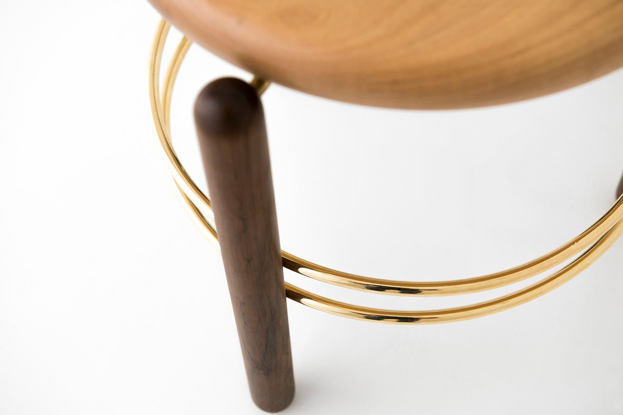 Brass and wood sculpted stool by Leandro Garcia
Materials: Cylindrical wood legs (dark color), wooden seat (light color), and polished brass hoops
Dimensions: 40 x 40 x 40 cm

The Linhas (“Lines”) stool is composed by three cylindrical solid wood