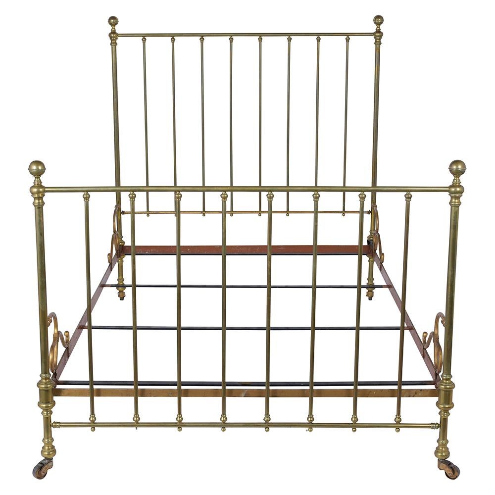 An antique European full-size bed frame. Beautiful crafted out of brass, this bedstead with decorative slender posts and round finials features head and footboard with beautiful patina original caster wheels in working condition wrought iron side