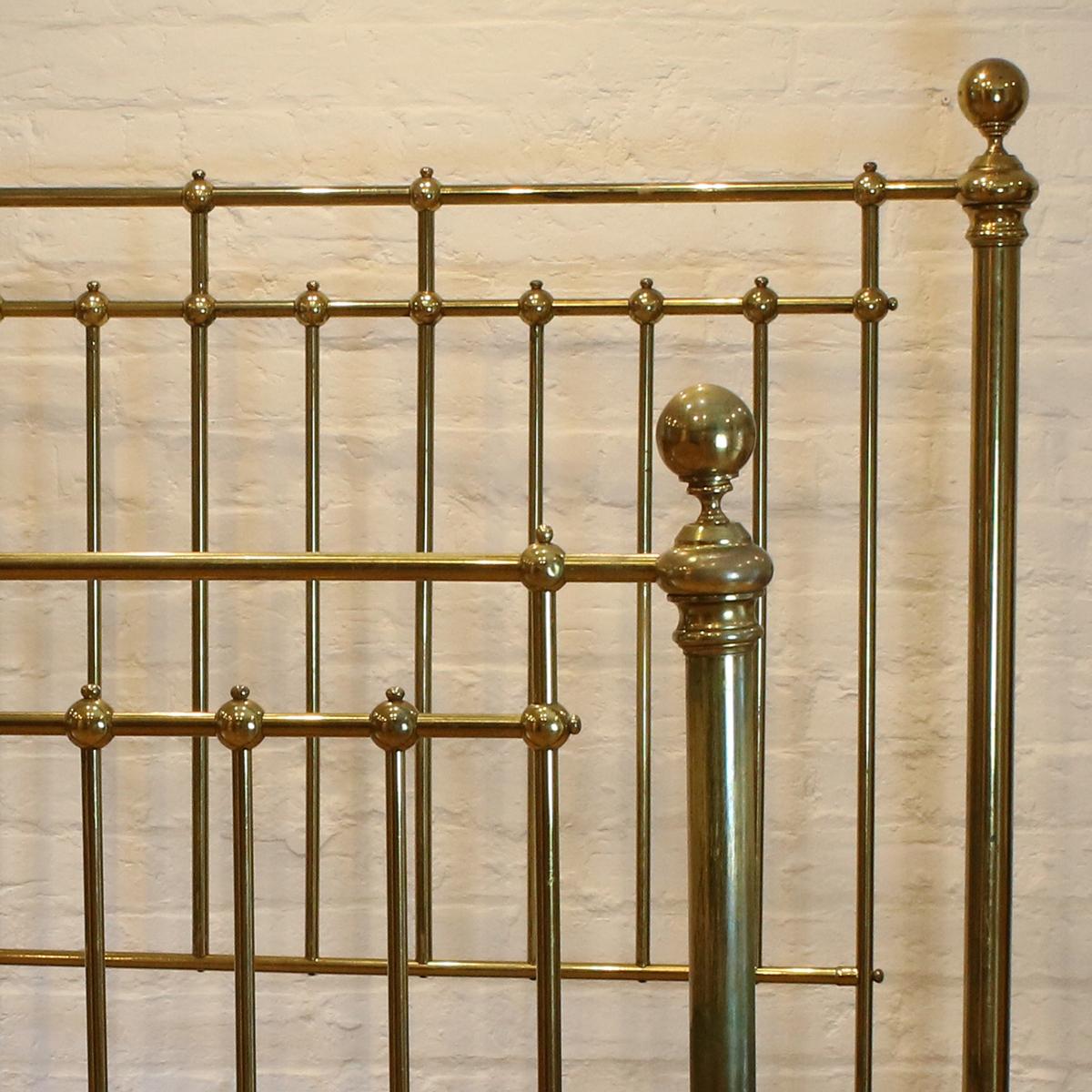 Antique brass bedstead with ball shaped castings, large 2 inch wide posts and central decorative feature on the foot panel. The original patina of the lacquer gives this bed an attractive overall golden hue. 

This bed accepts a British king size or