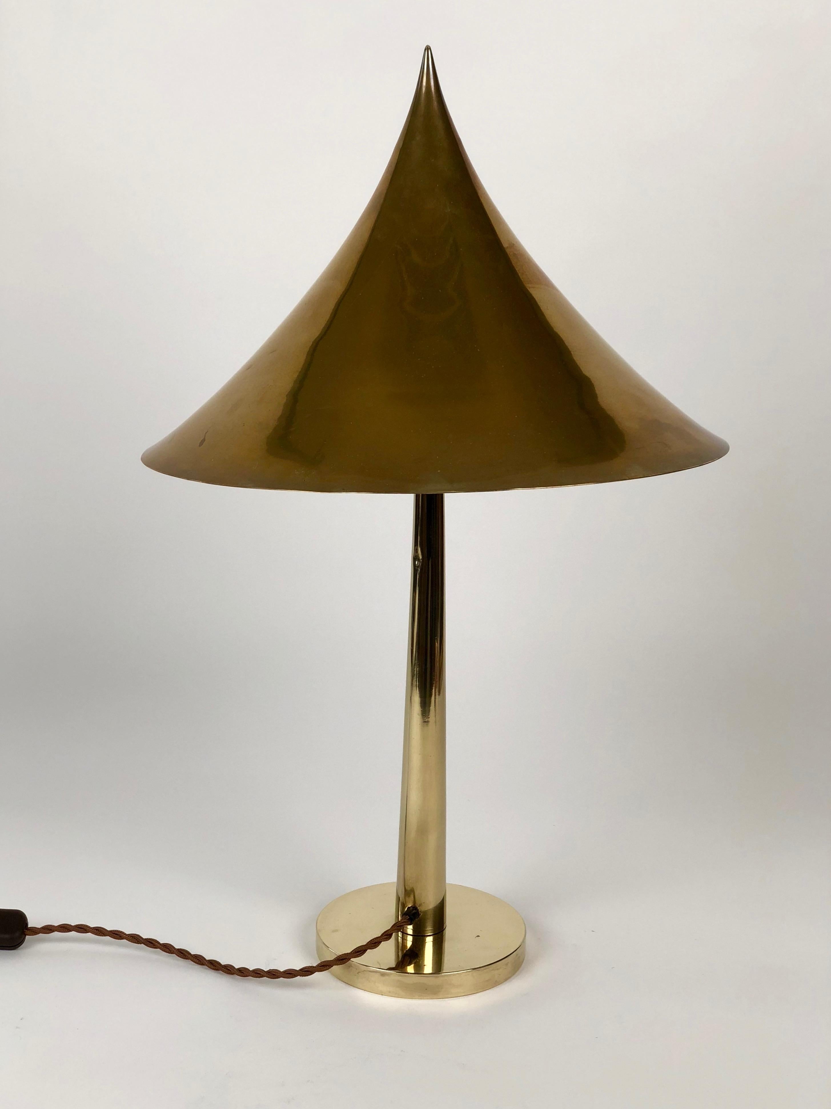 Lampe de table de la société August Melzer, Vienne Autriche, ca 1910/1915. 
L'abat-jour est un cône pointu réalisé en laiton, il est supporté par un tapeur
un arbre qui est fixé à une base cylindrique. Ces trois éléments sont parfaitement