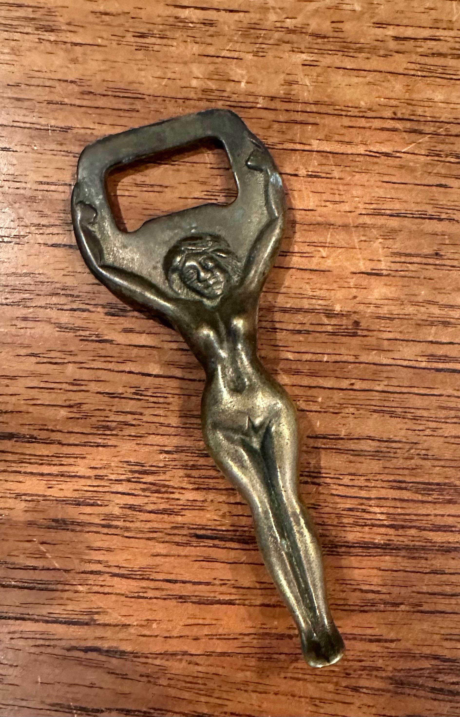 Un divertido abridor de botellas de latón art decó de mujer desnuda, de hacia 1940. La pieza está en muy buen estado vintage, con una gran pátina, y mide 1,5