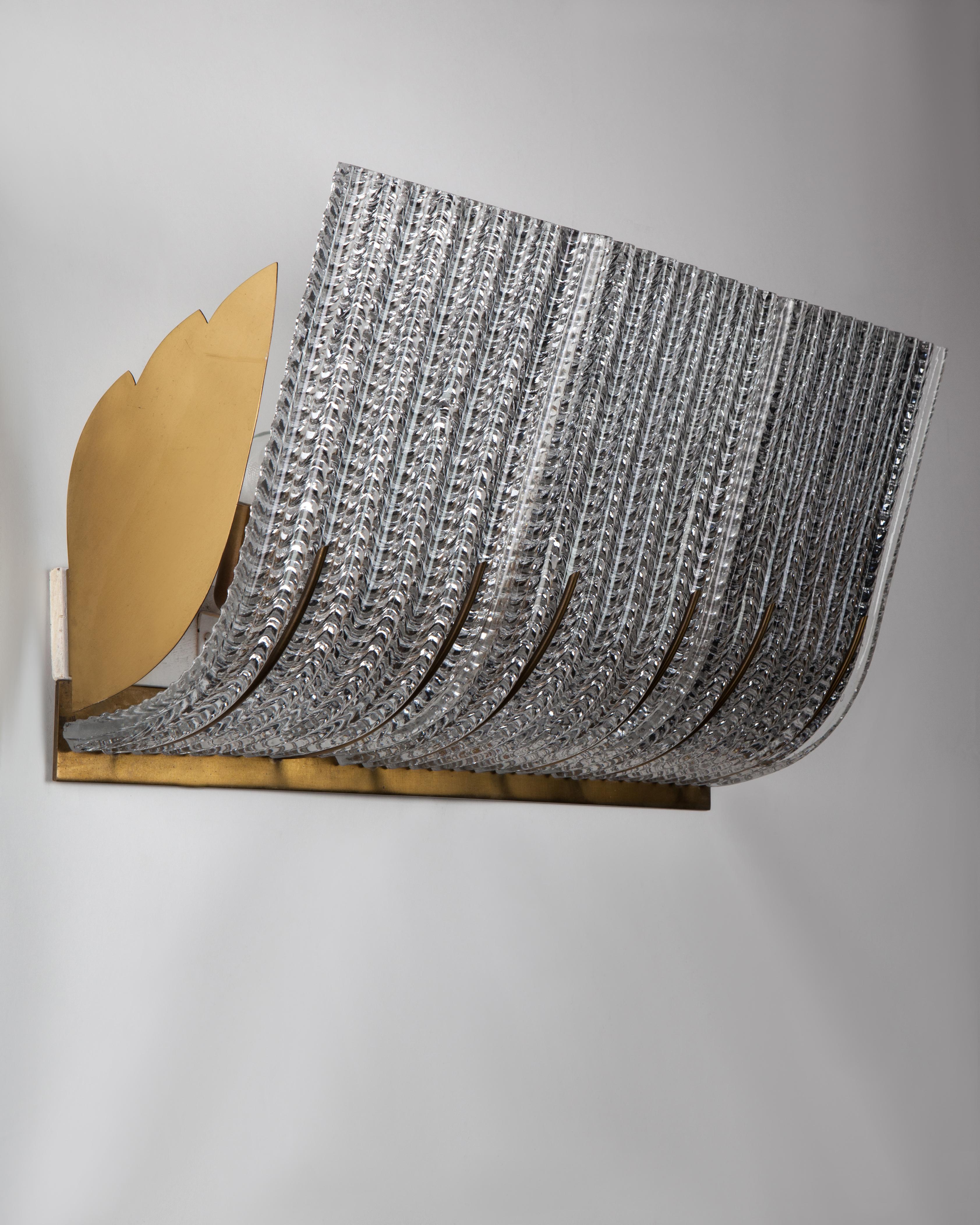 AIS2990
A large wall light with textured upswept glass panels in a wing-shaped brass frame. Due to the antique nature of this fixture, there may be some nicks or imperfections in the glass as well as variations from piece to