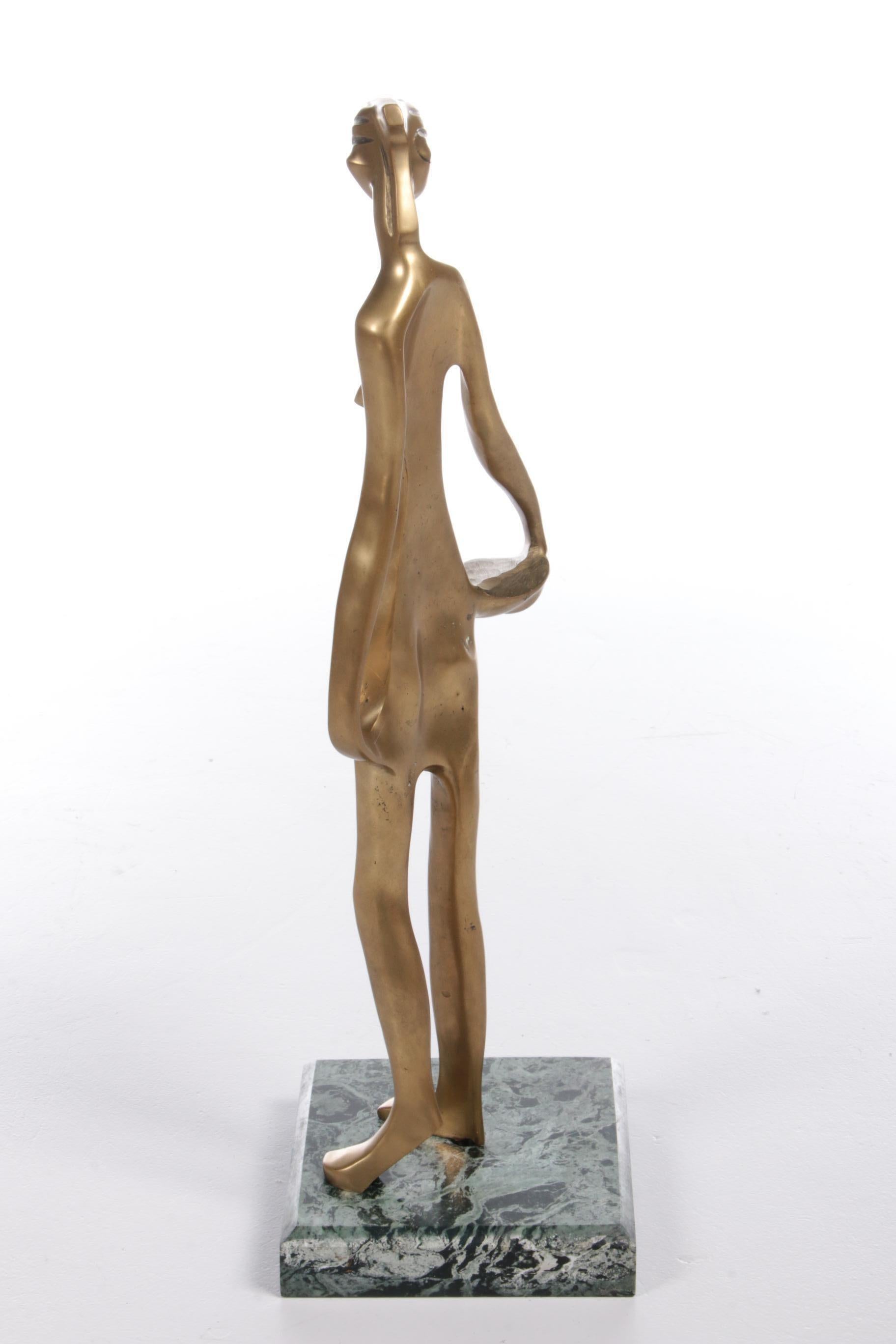 A beautiful statue made of gold-coloured brass. It is a representation of an African female figure.

The statue is made in the style of Franz Hagenauer, who designed many African statues himself and is known for his special works. The style with