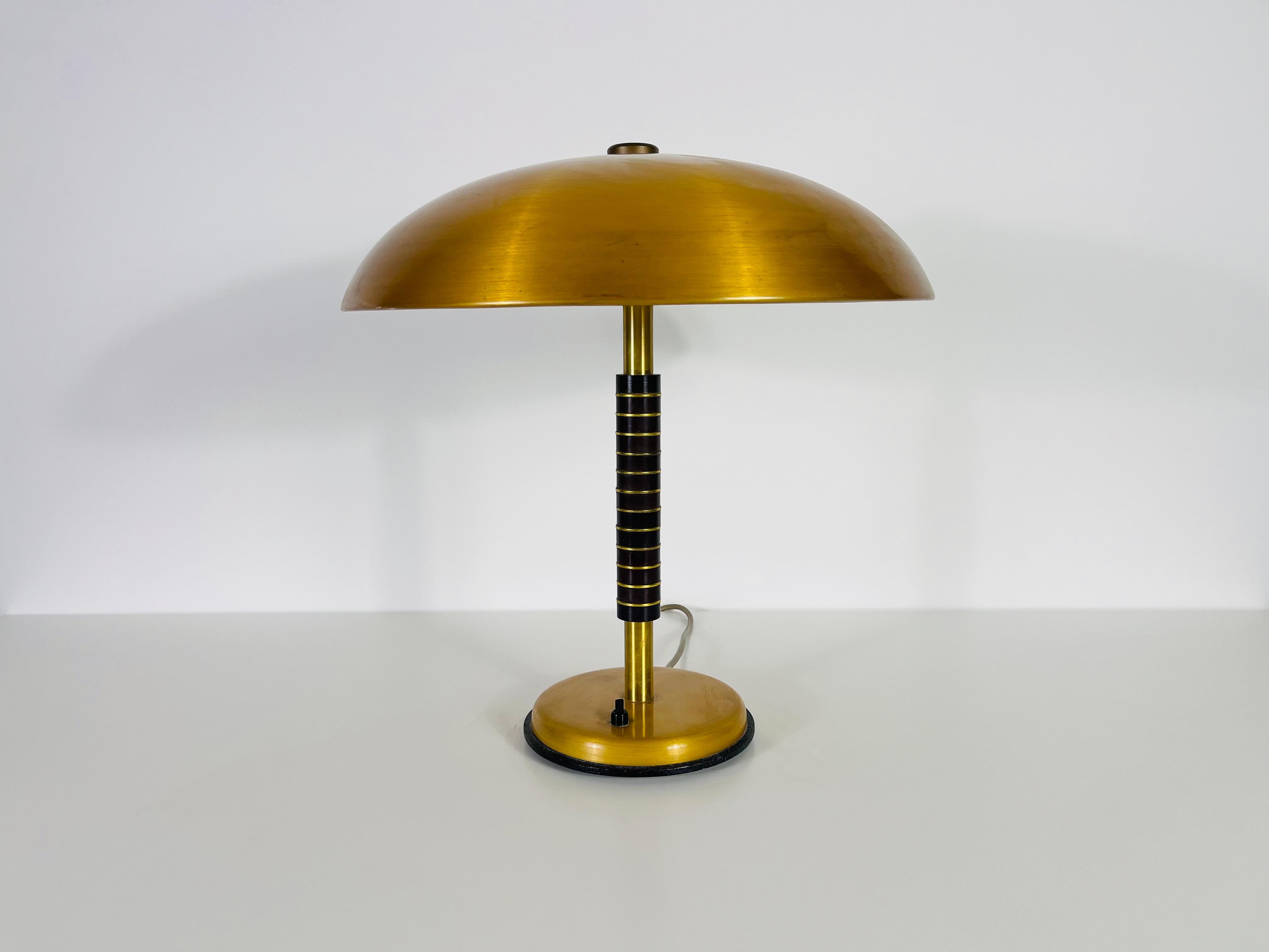 Cette lampe de table Art Deco, fabriquée en Allemagne dans les années 1950, présente un design saisissant influencé par l'esthétique du Bauhaus. Fabriqué en laiton et en plastique dur, il utilise des matériaux provenant de restes de production de la