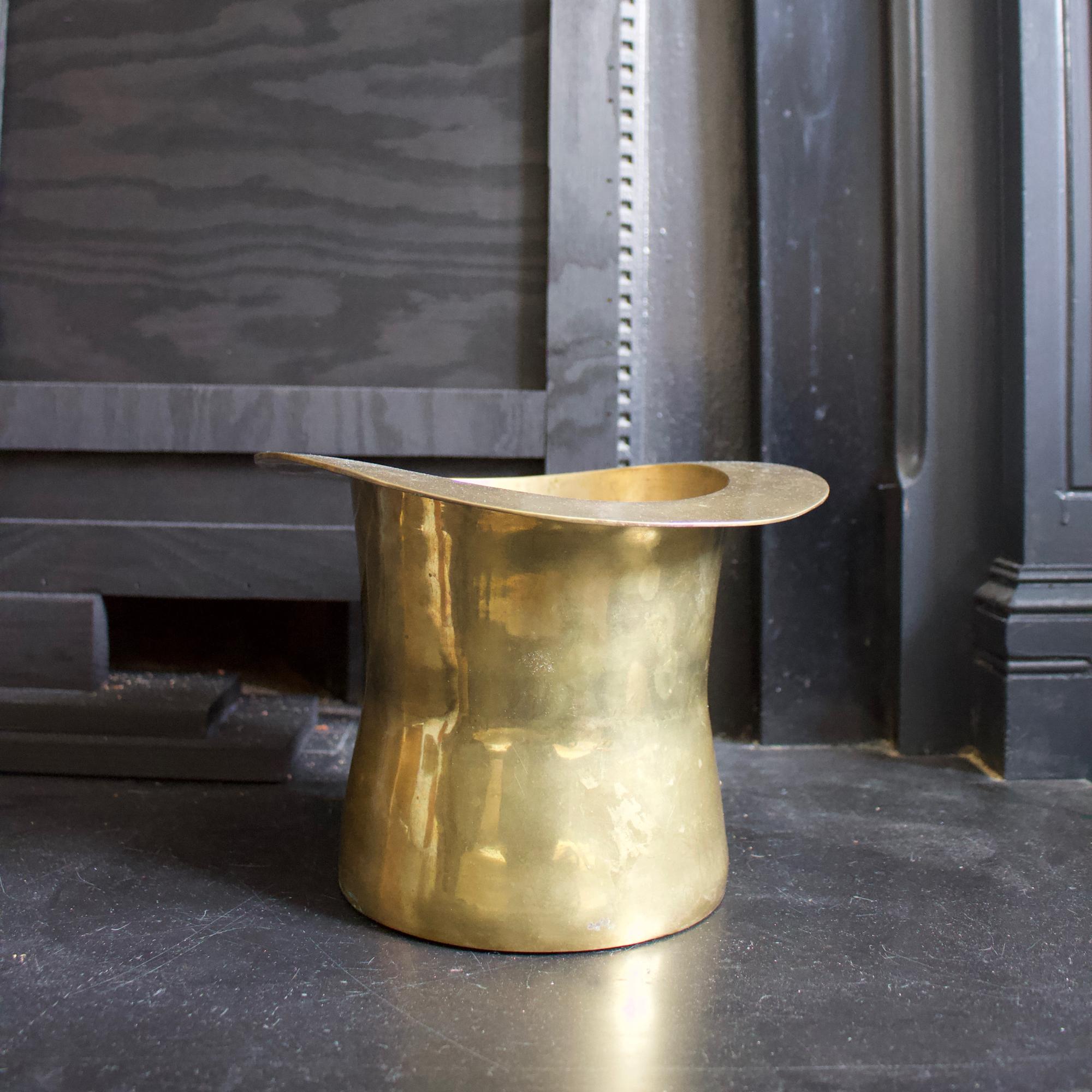 Brass champagne or ice bucket in the shape of a top hat, early to mid-20th century European.

Nice simple design - very much Art Deco style - with a handcrafted appearance. Good vintage condition with age appropriate signs of wear; some surface