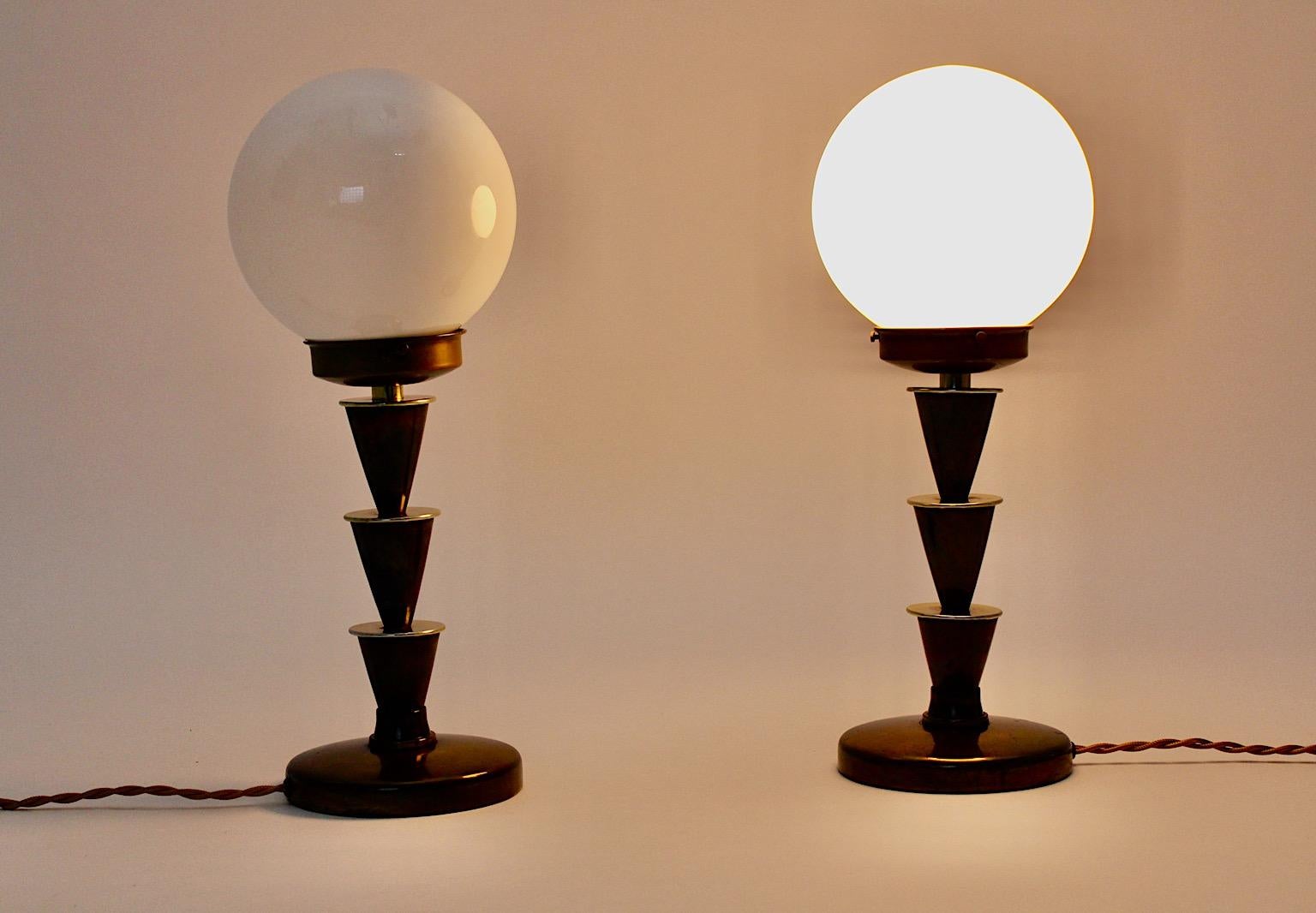 Art Deco pair of table lamp geometric style lollipop from brass with white round like opal glass shades 1930s Vienna.
While the geometric like metal bases show beautiful brass patina, the opal glass shades have no damage. Three screws hold each