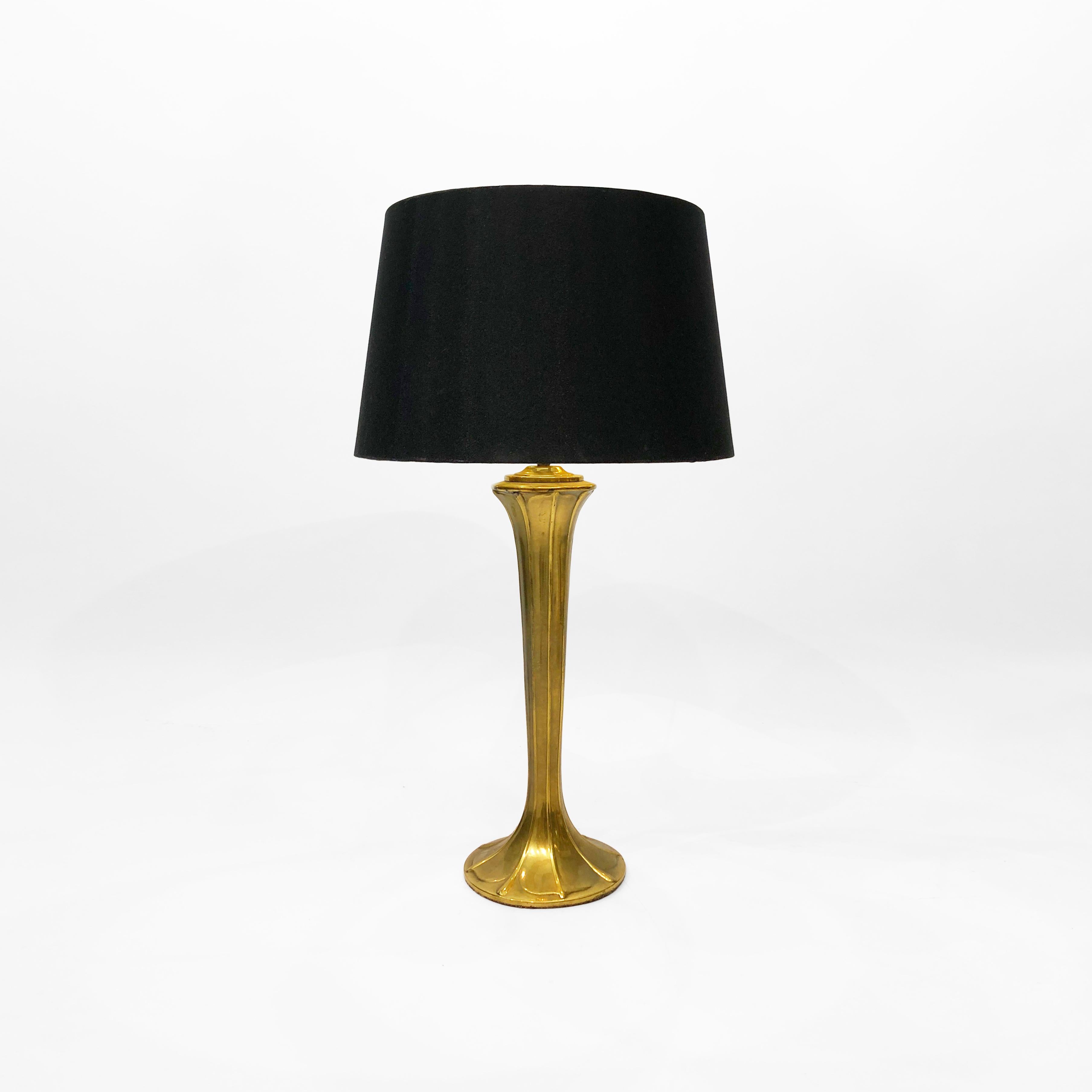 An Art Nouveau-inspired table lamp from the 1970s, composed entirely of brass. The organic, torchesque lamp gently curves inwards from the bottom, in an embossed leaf-like manner, before widening again where the bulb fitting is. The simple,
