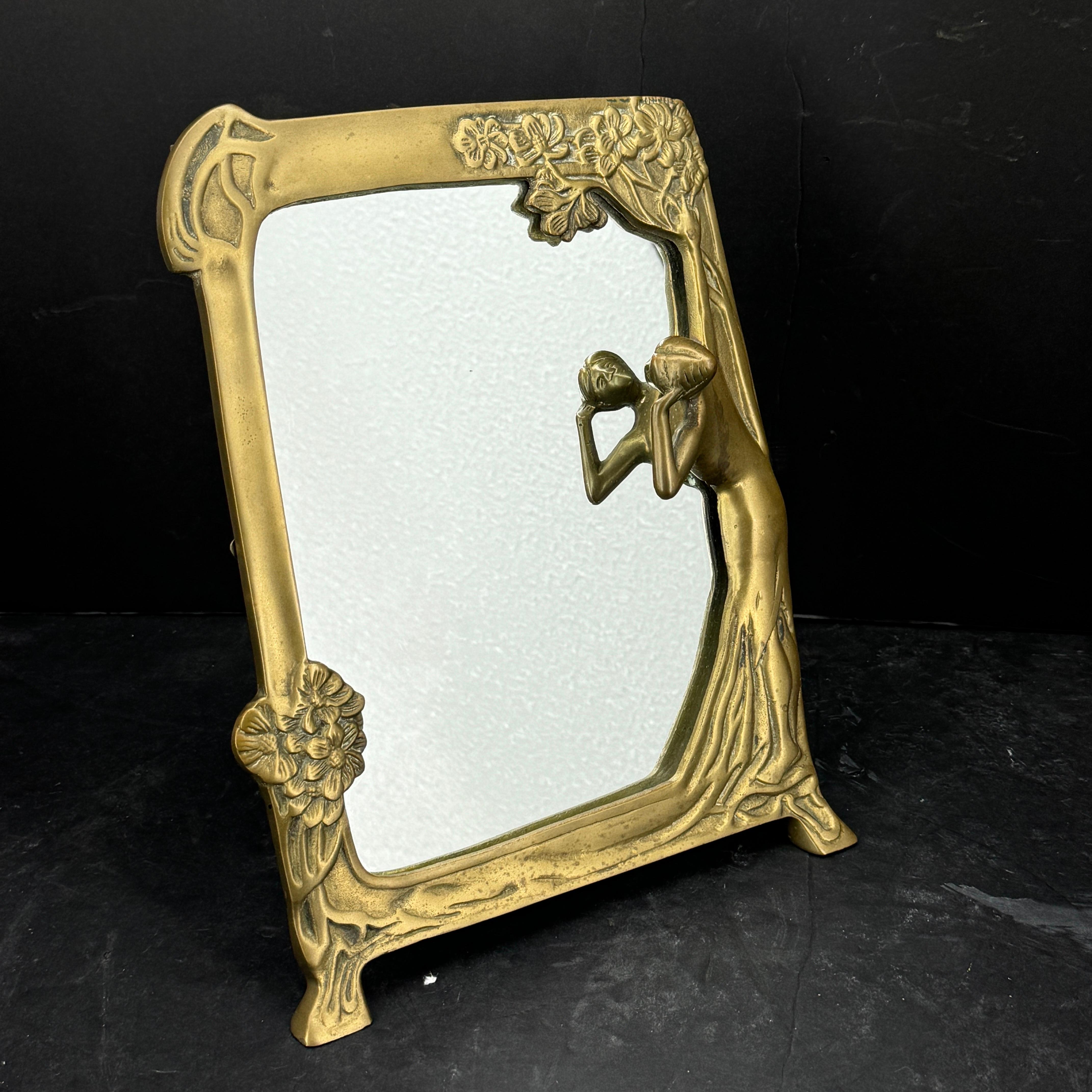 Elegant brass vanity mirror featuring a woman with a floral motif surround. The mirror is sturdy and is as comfortable resting on top of a dresser, bathroom counter or office credenza. Certainly an excellent addition to Art Nouveau decor in a home