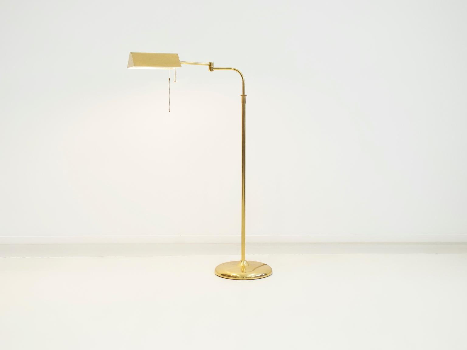 'Banker' floor lamp from the 1970s. Brass construction with round stand, height-adjustable arm and a swiveling shade, equipped with one light point and a pull switch. Height can be adjusted from 100 to 155 cm.