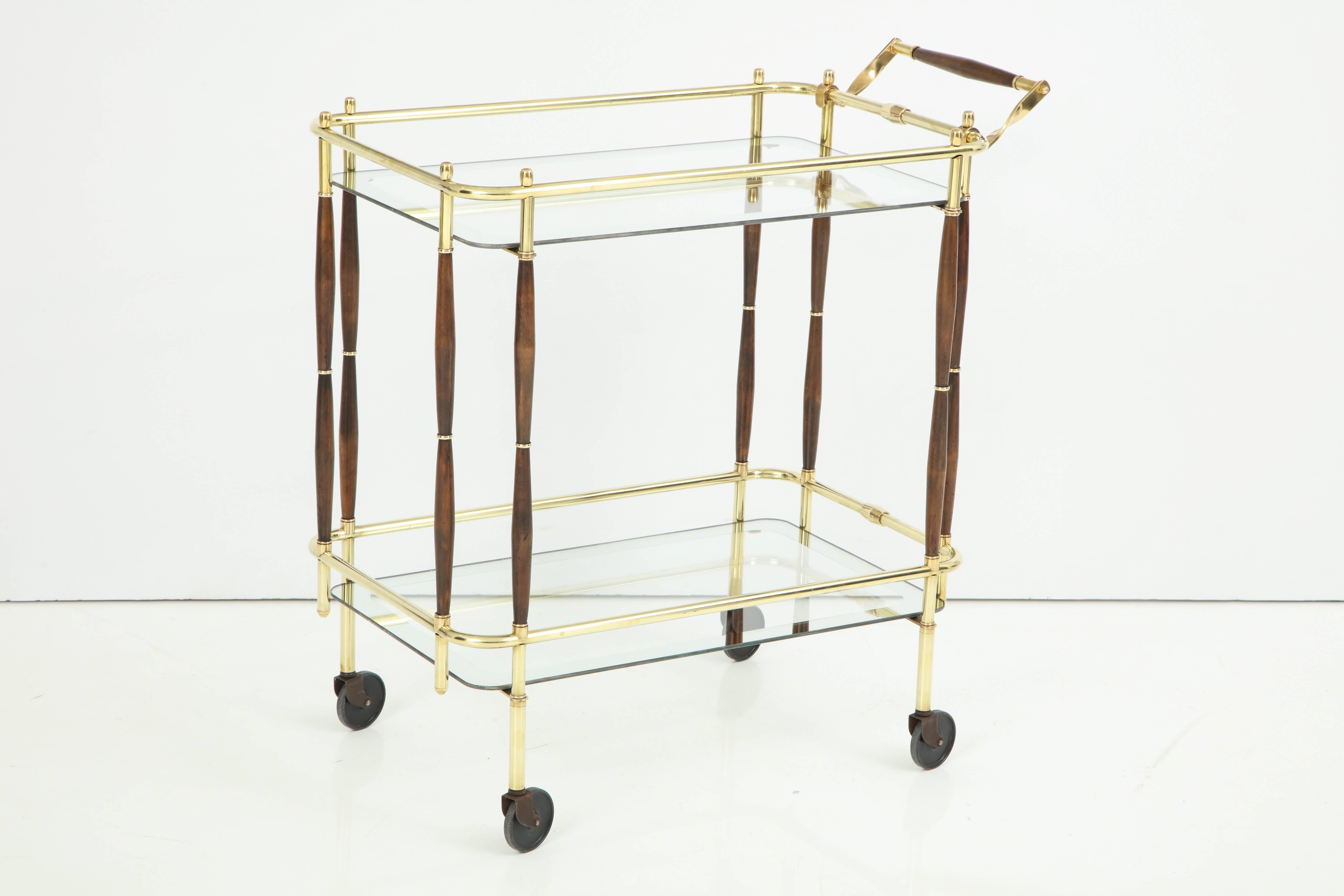 Decorative brass, midcentury bar cart with dark wood details, circa 1950. Very good condition. Handle is 33.5 inches high.
Glass tops have decorative silver edges, 1.5 inches wide borders.