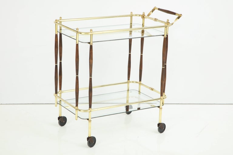 Decorative brass, mid-century bar cart with dark wood details, circa 1950. Very good condition. Handle is 33.5 inches high.
Glass tops have decorative silver edges, 1.5 inches wide borders.