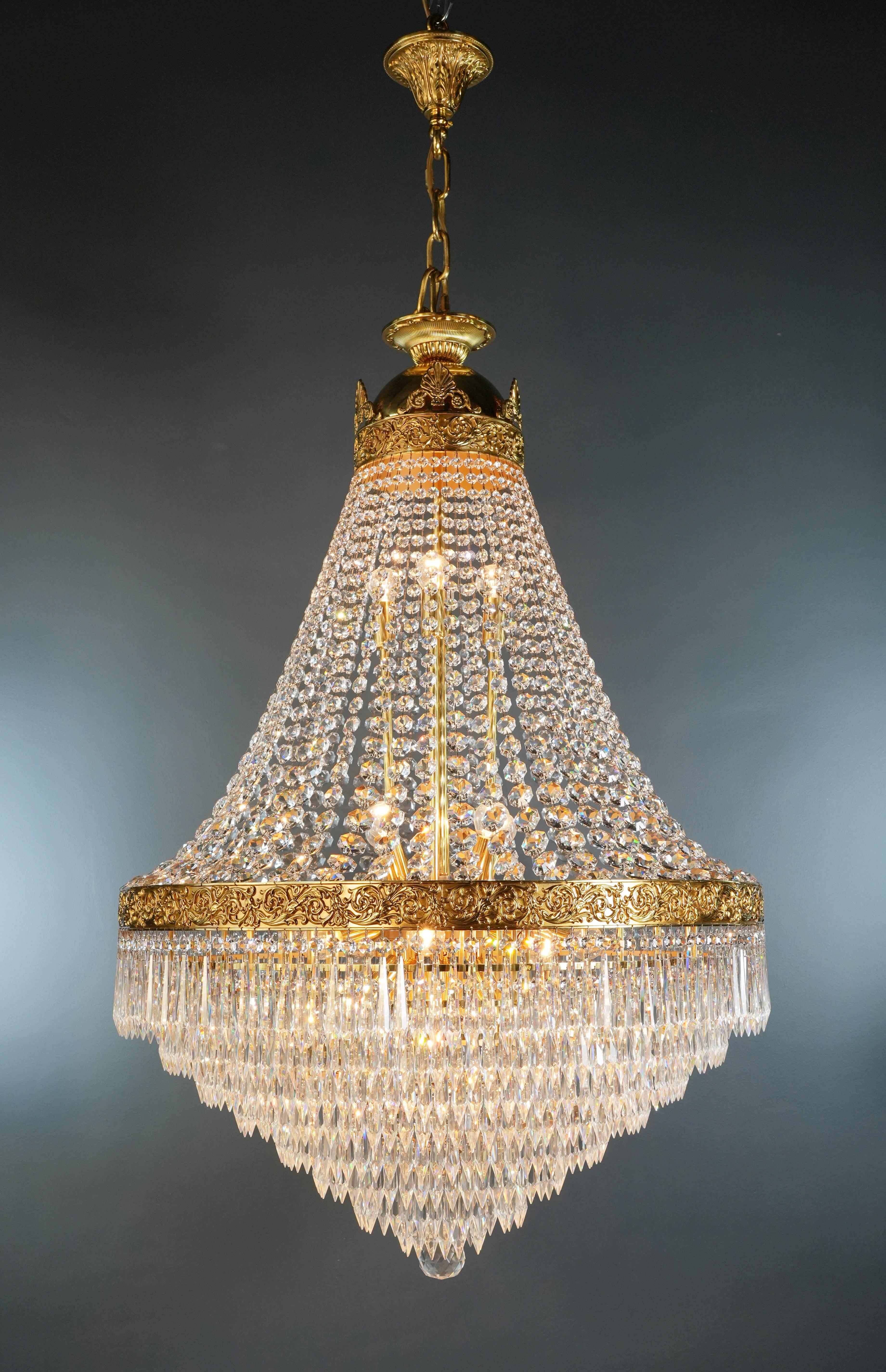 Introducing a stunning Brass Basket Empire Sac-a-Pearl Chandelier, an exquisite piece adorned with mesmerizing crystals, evoking the classic style of the Empire era. This is a new reproduction and there are several available to ensure you can bring