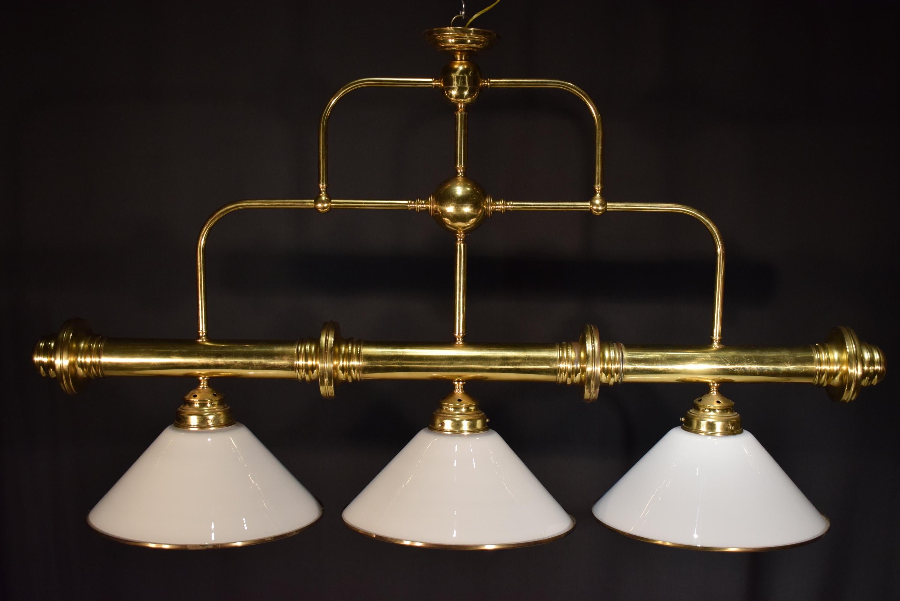 A very fine brass billiard or over kitchen island chandelier. Featuring 3 white glass conical shades fitted with brass rim. England, circa 1930.
Dimensions: Height 36 1/2