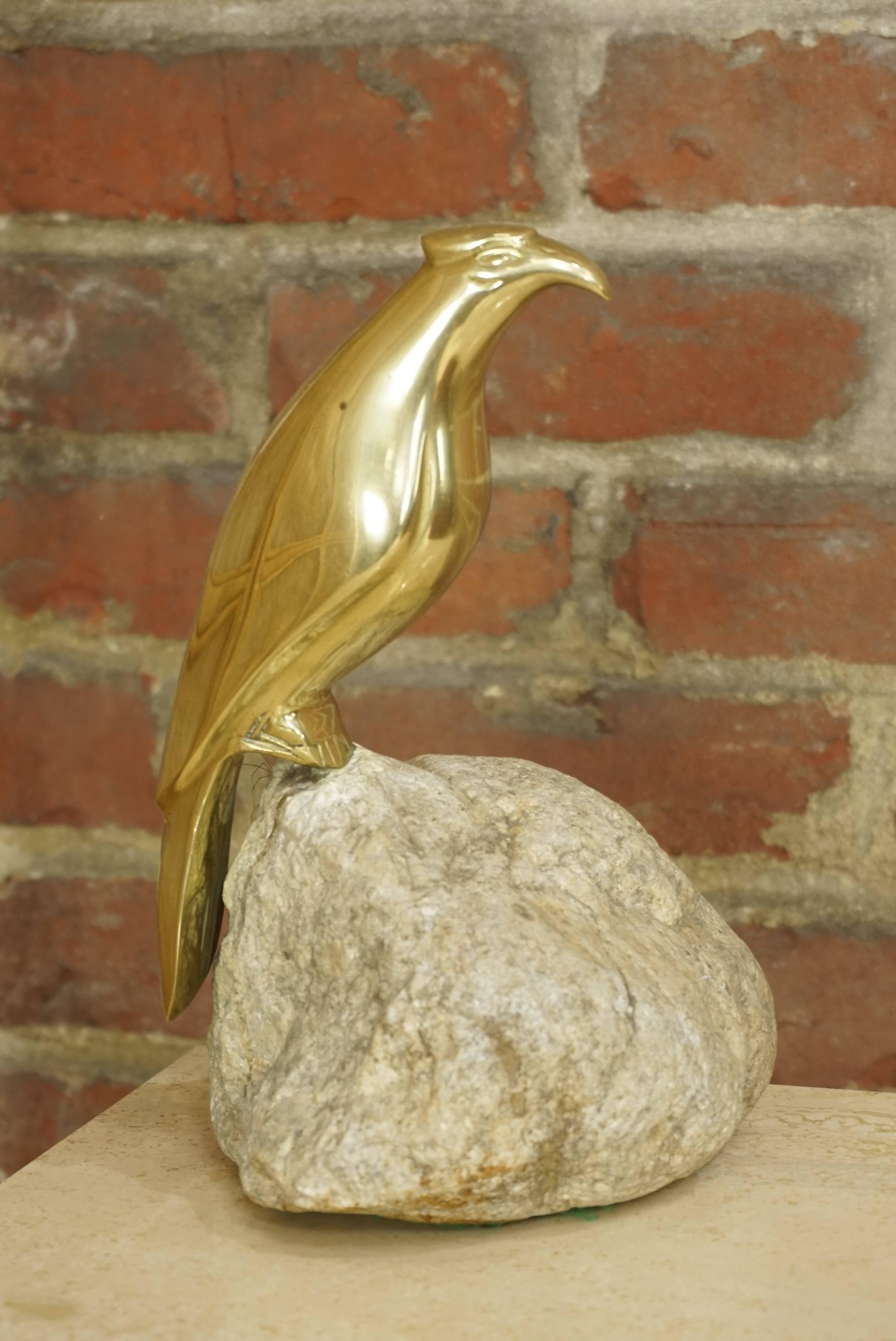 Brass sculpture bird on stone.