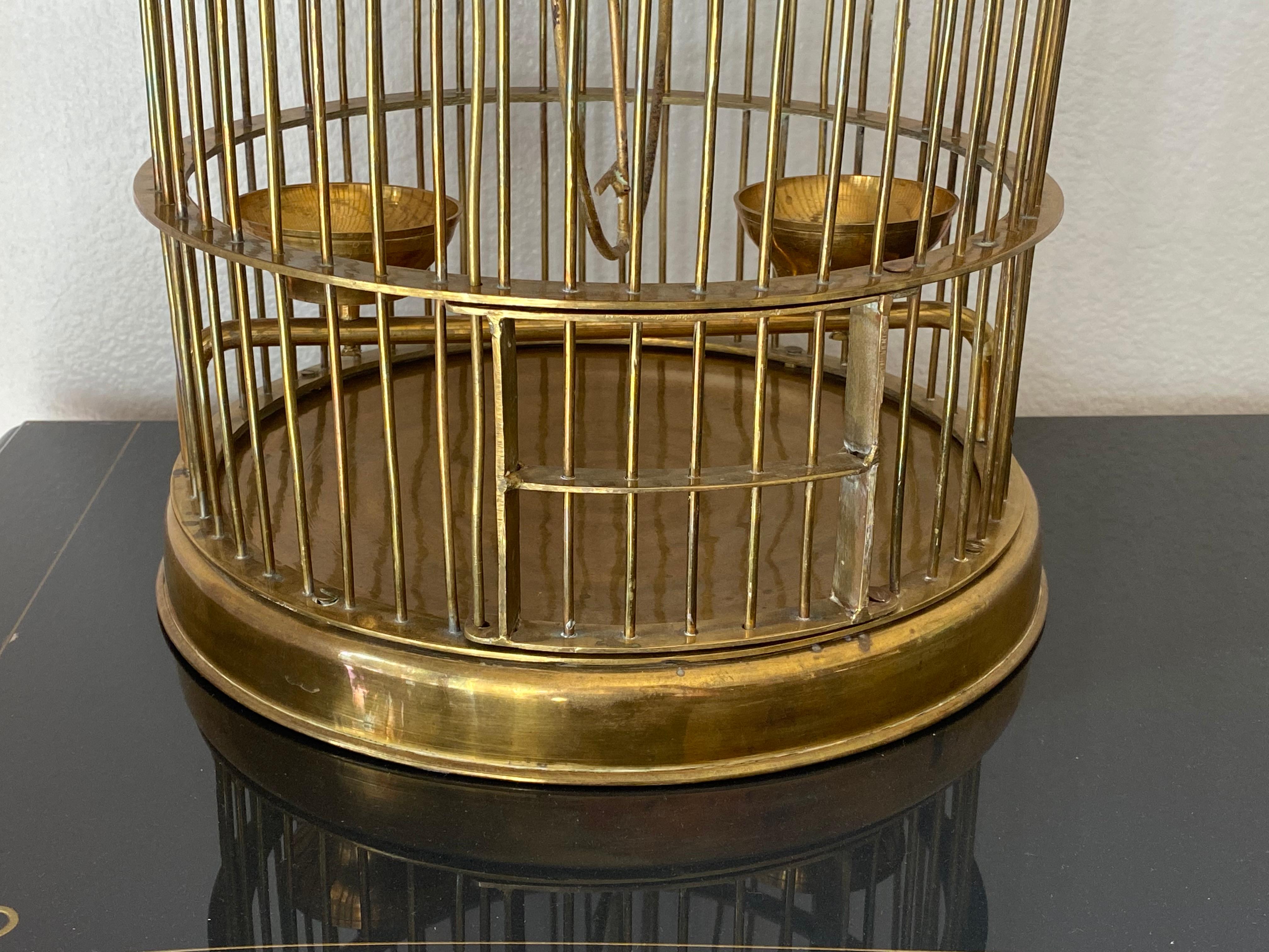 Decorative brass birdcage with swinging door.