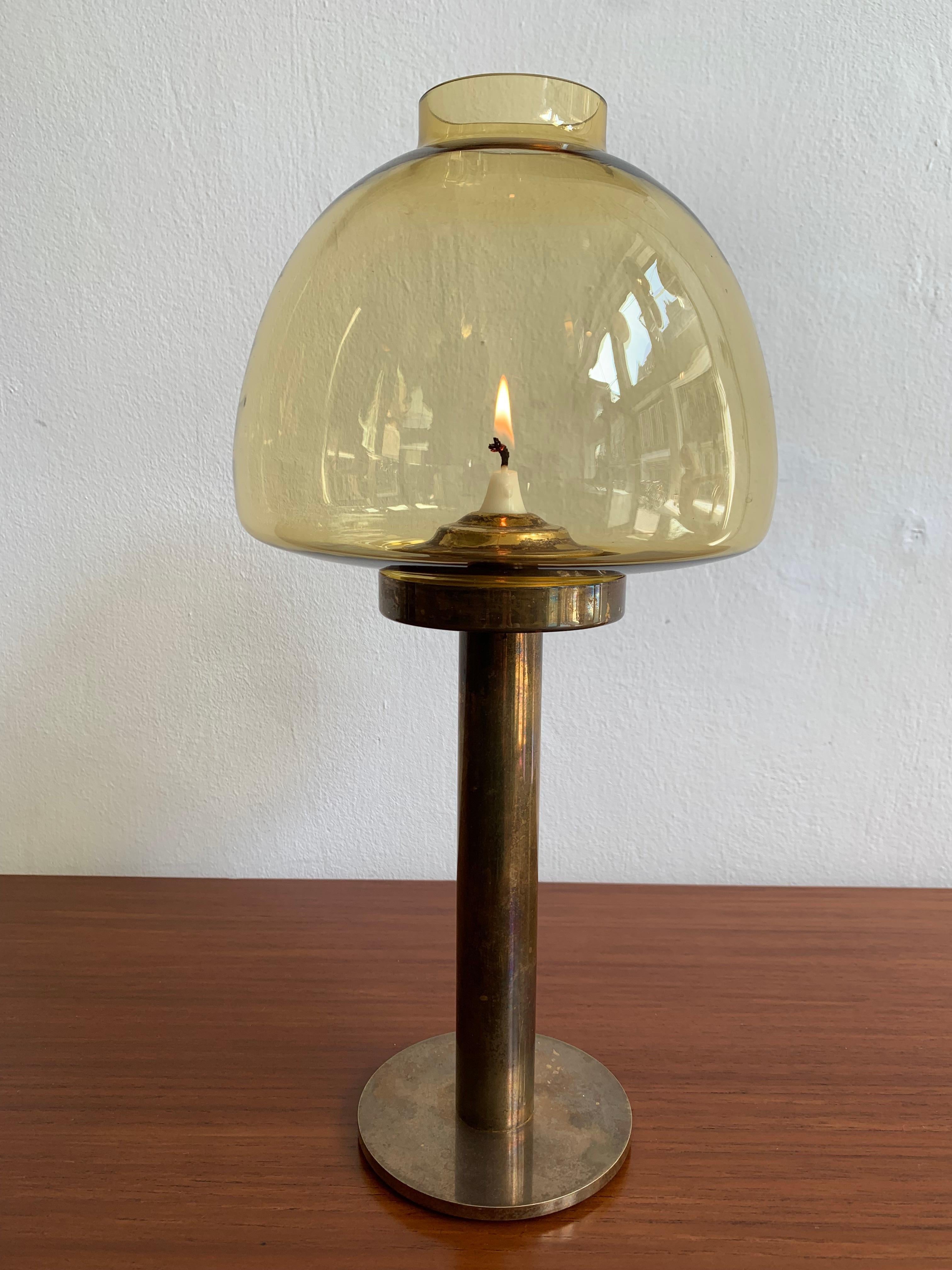 Hurricane candle lantern / candle holder model L102/32 by Swedish designer Hans-Agne Jakobsson made from heavy solid brass with ochre-yellow mouth-blown glass shade. 
The candle burns continuously because the brass base interior's are executed with