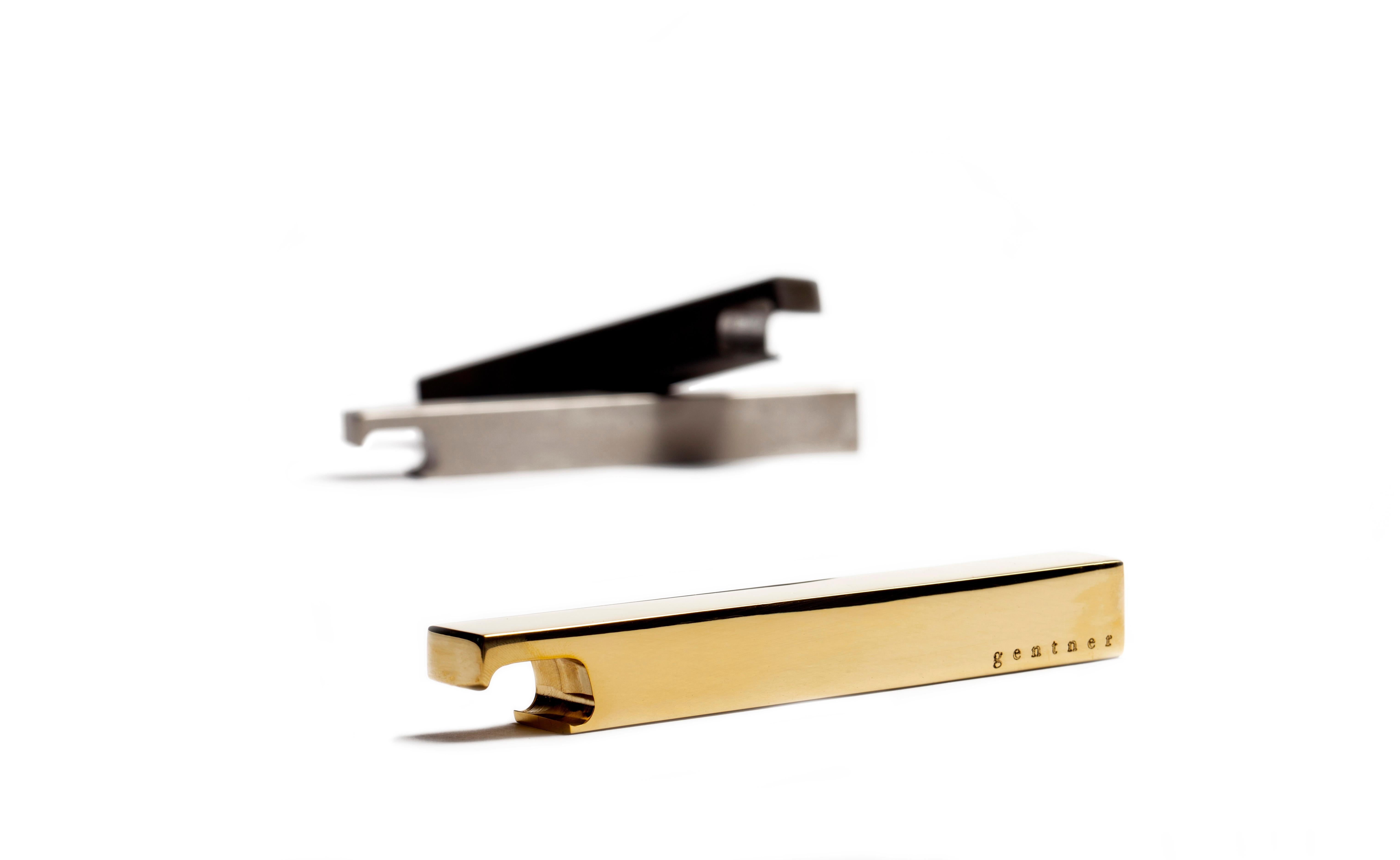 Brass bottle opener by Gentner Design.
Dimensions: D 14 x W 1.9 x H 1.9 cm.
Materials: polished brass.

Strong in form and heavy in weight, the bottle openers are elegant in their simplicity and precision. Solid bar stock is transformed through