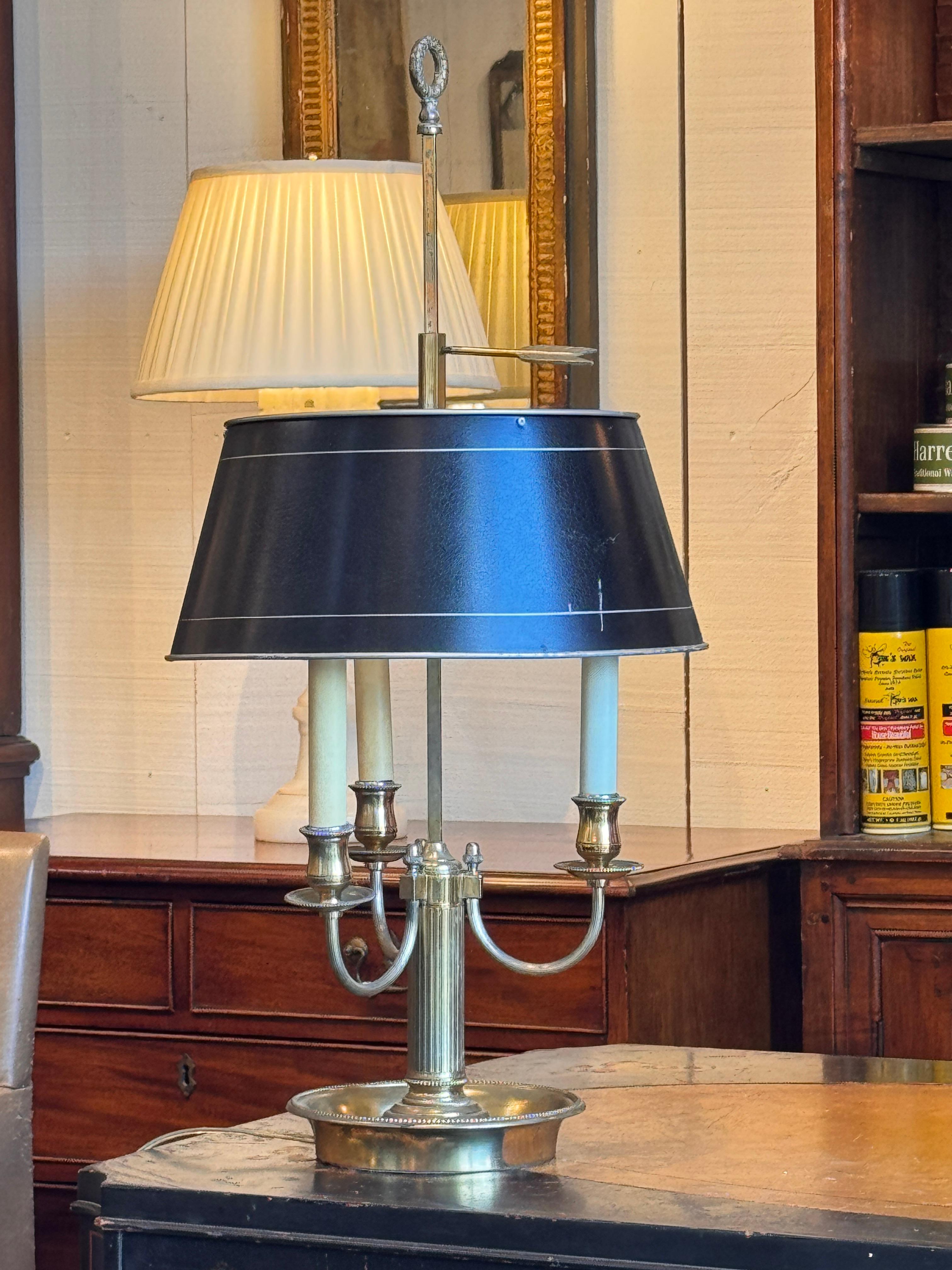 Classic brass bouillotte lamp featuring three curved candle-style arms, beaded details, and a painted tole shade with arrow-form height adjuster.
