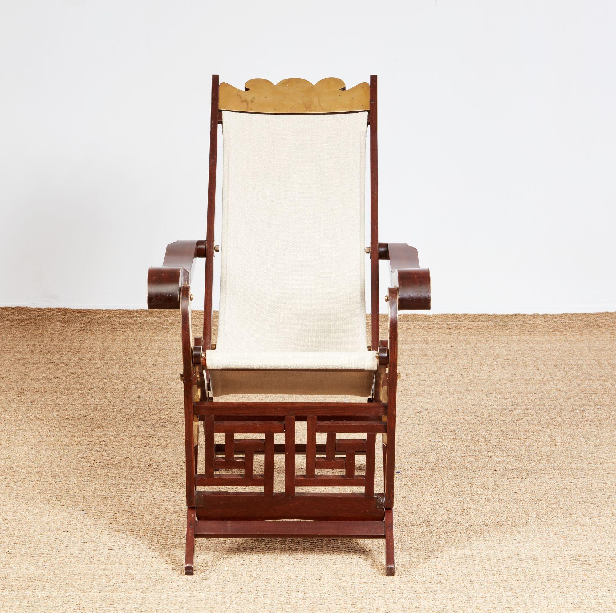 Notable sillón plegable de terraza/campaña de madera noble exótica del siglo XIX, posiblemente de exportación china, con cresta festoneada y placa de latón, respaldo tapizado con brazos en forma de volutas montados en latón, armazón plegable con