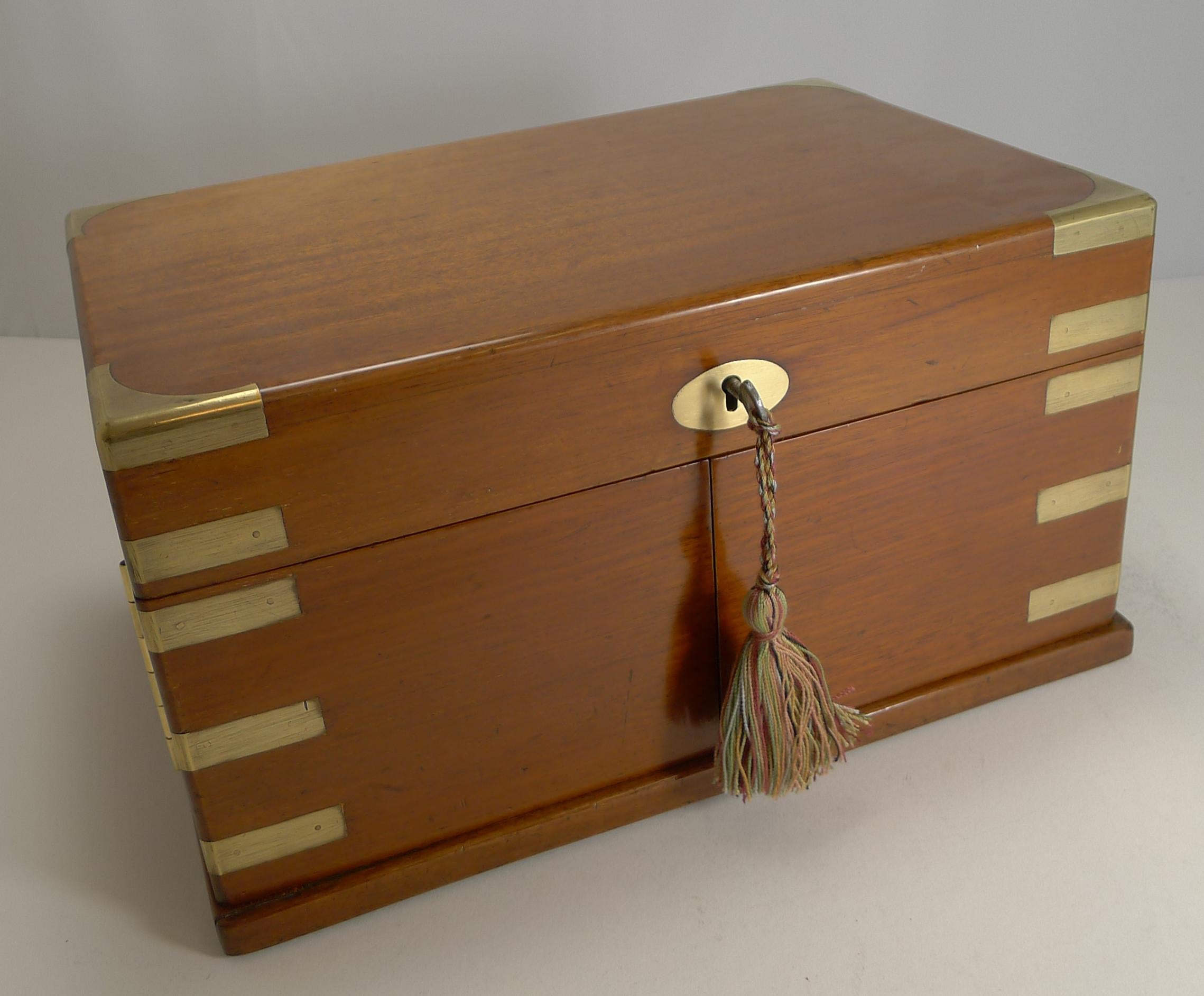 A striking and unusual late Victorian English games box made from mahogany with military or campaign style brass inlay; these box are usually plain, this one being a little more special than the rest.

The lid lifts to reveal the folded leather