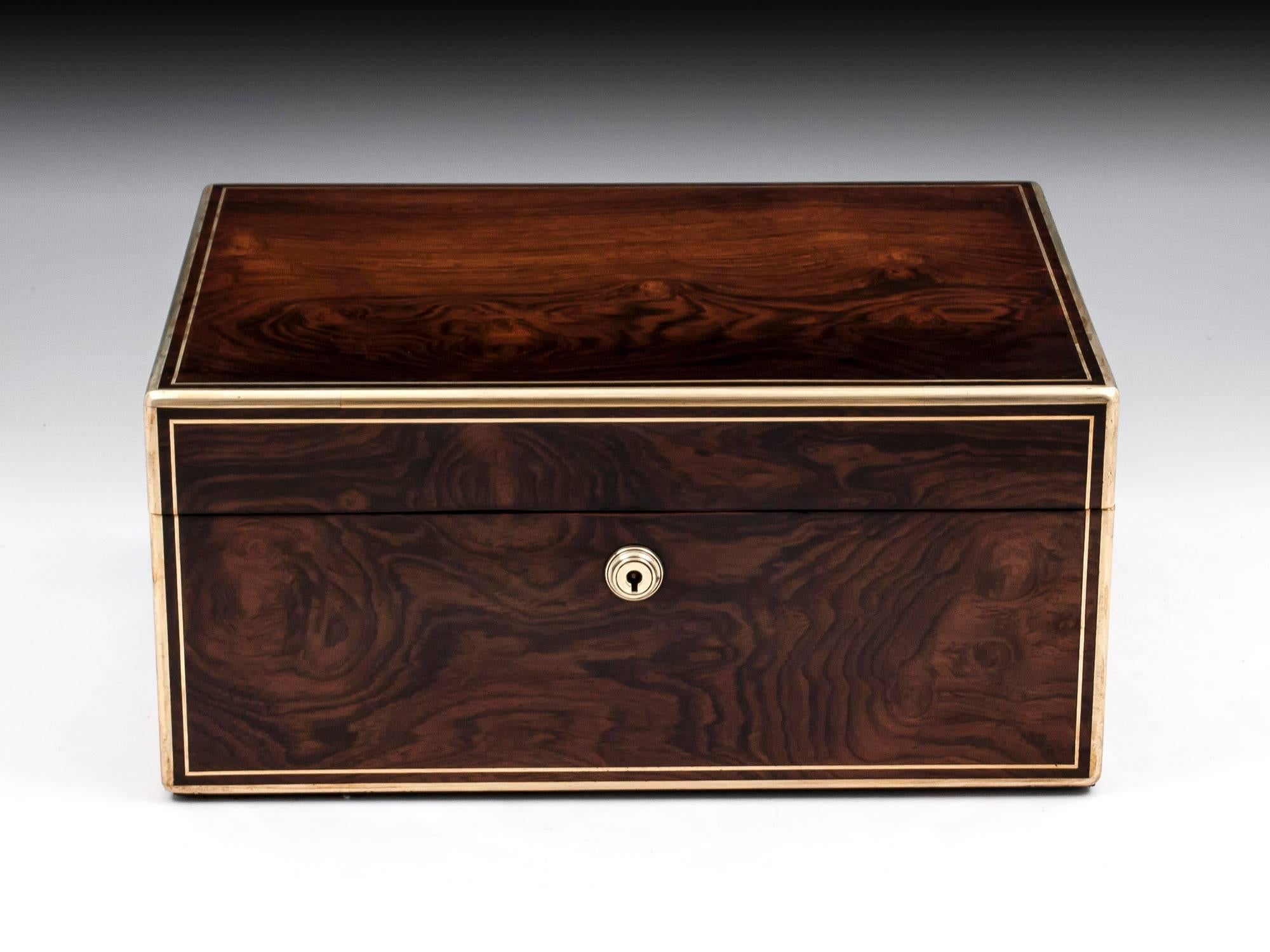 Antique Jewelry box veneered in stunning figured mahogany, with rounded brass edging, stringing, escutcheon and flush fitted campaign carry handles.

The interior is lined in sumptuous padded maroon velvet and silk paper. Featuring a removable